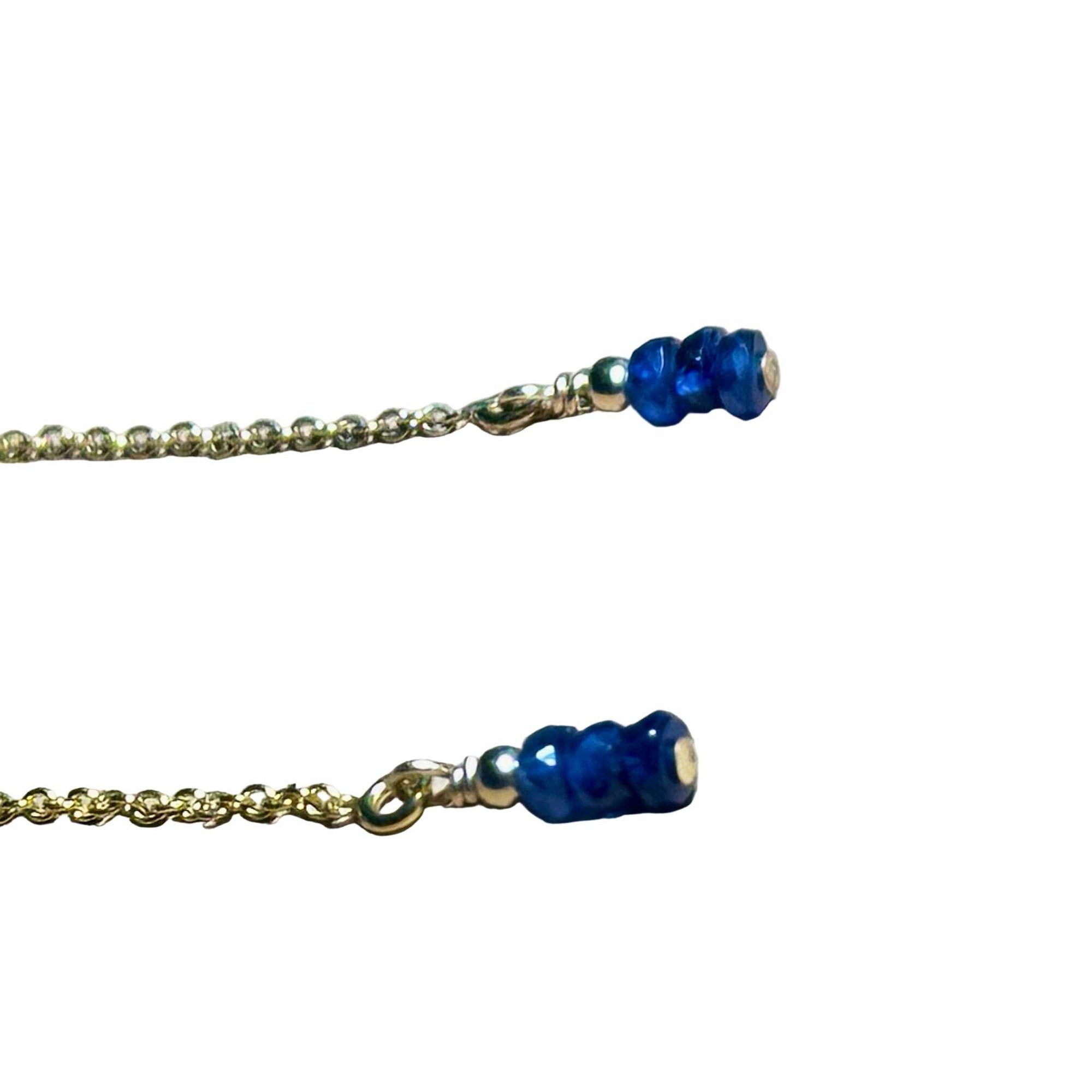 Gold chain earrings with blue Sapphire beads on a background.