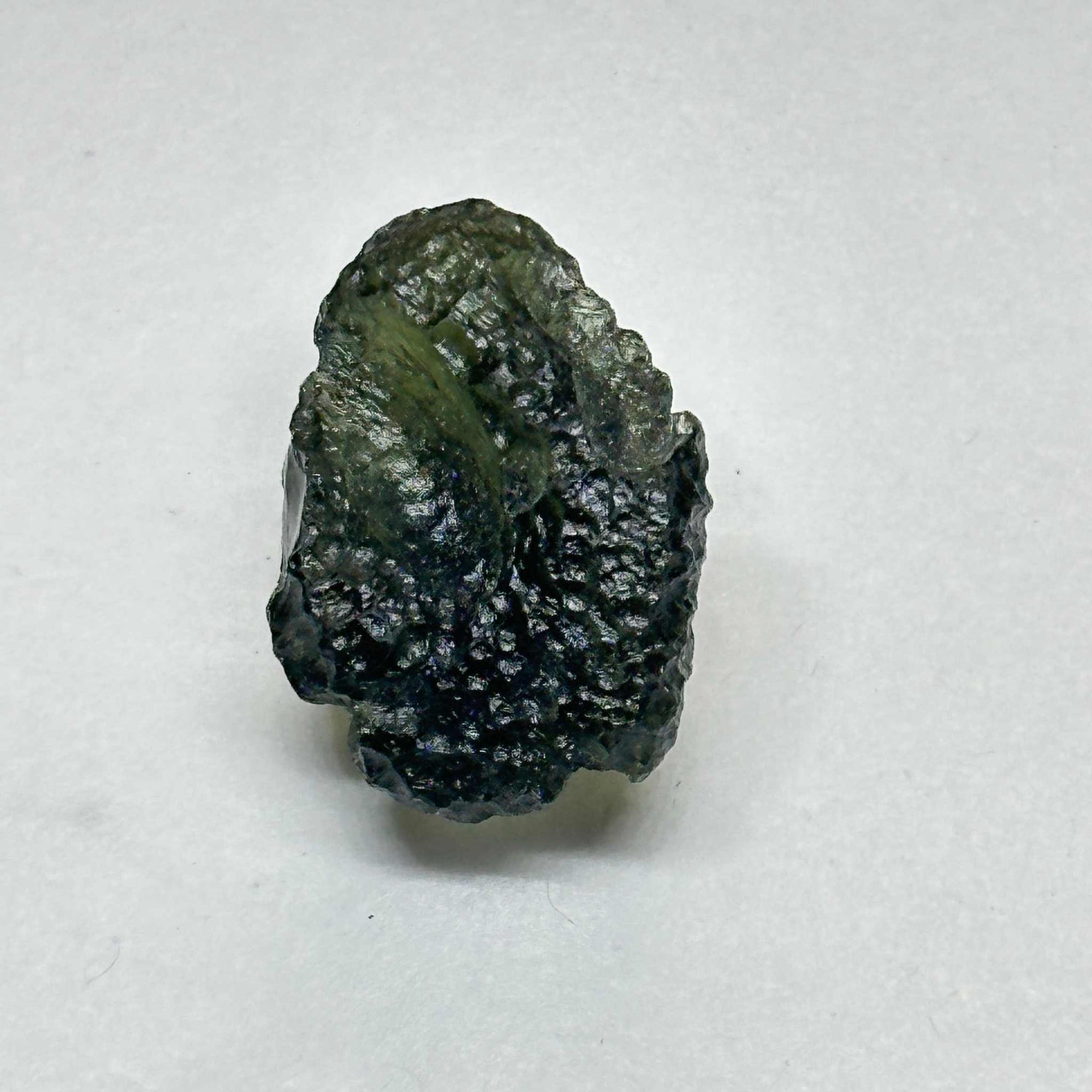 Raw Moldavite tektite stone weighing 4.076 grams with a dark green, textured surface.