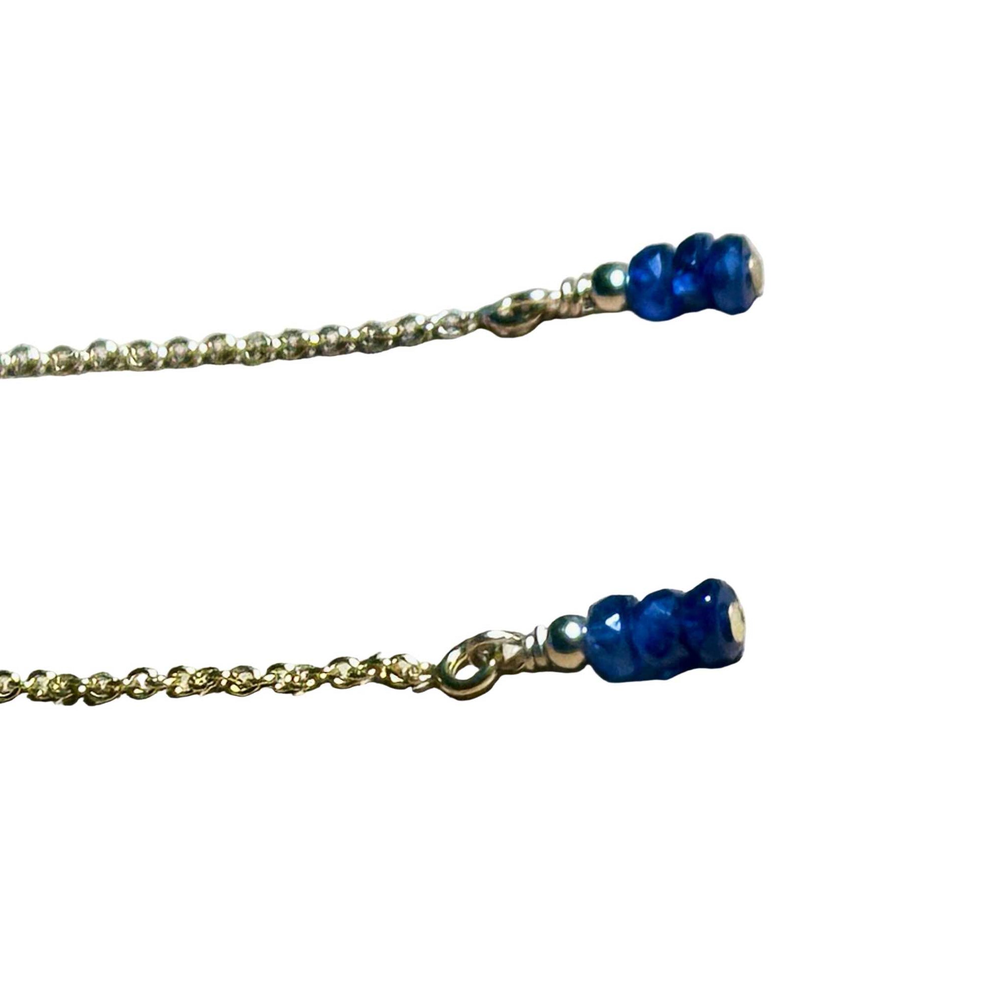 Gold chain earrings with blue Sapphire beads on a background.