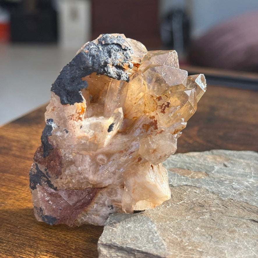 Natural Kundalini Citrine Shield Cluster with hematite inclusions on a wooden surface.