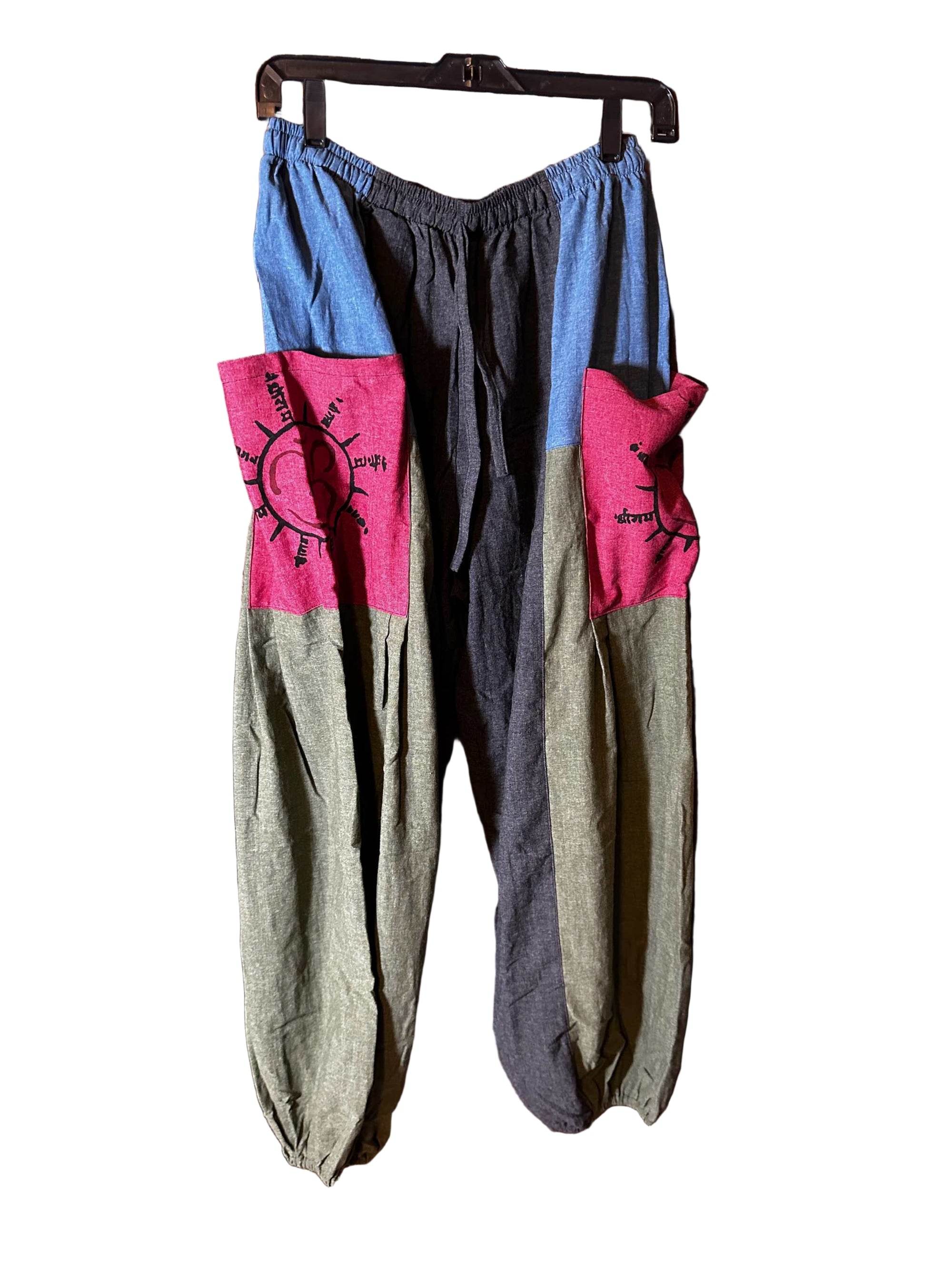 Multicolored Cotton Ohm Pants with sun and symbol designs hanging on a wooden background