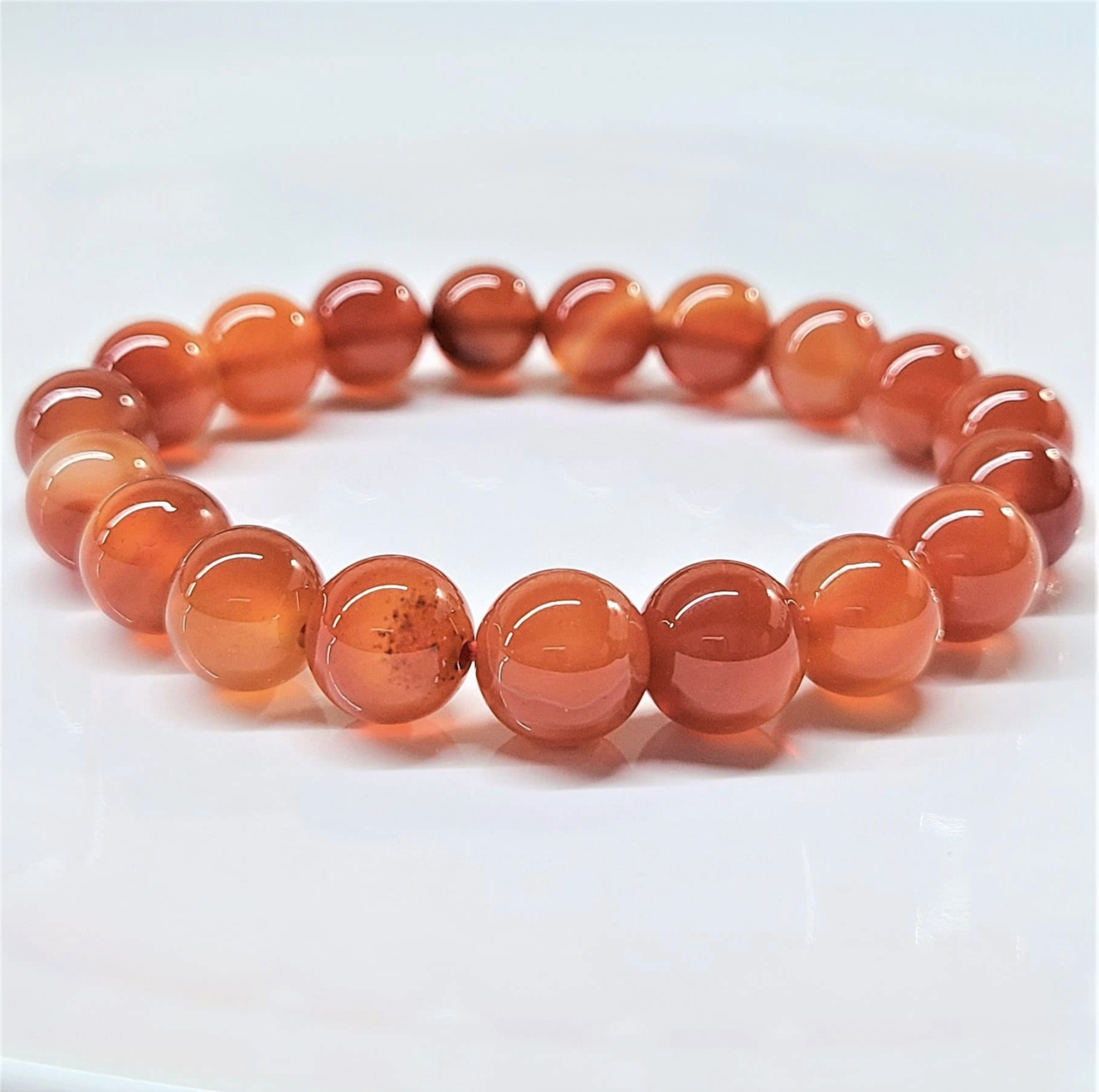Carnelian stackable bracelet with smooth round reddish-orange beads on elastic band