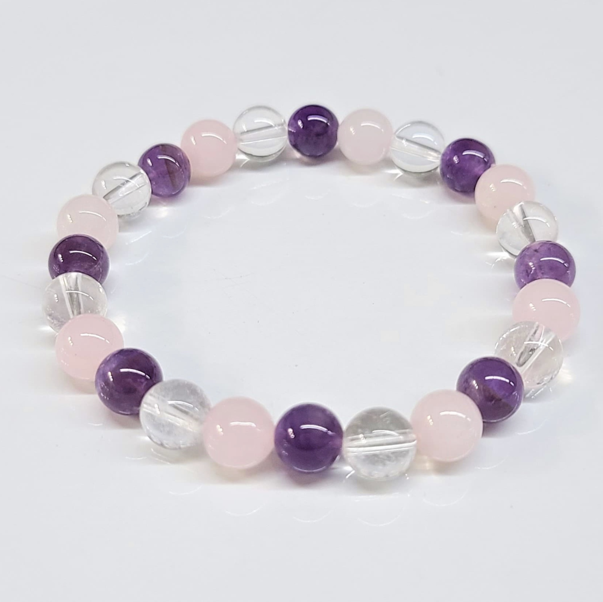 Round bead bracelet featuring 8mm Amethyst, Clear Quartz, and Rose Quartz stones in a stackable design.