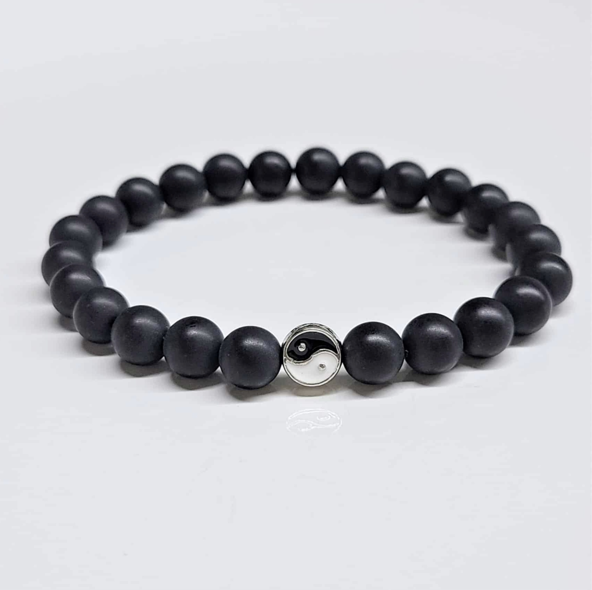 Smooth black lava stone bead bracelet with 8mm beads and a central Yin Yang symbol charm for balanced protection.