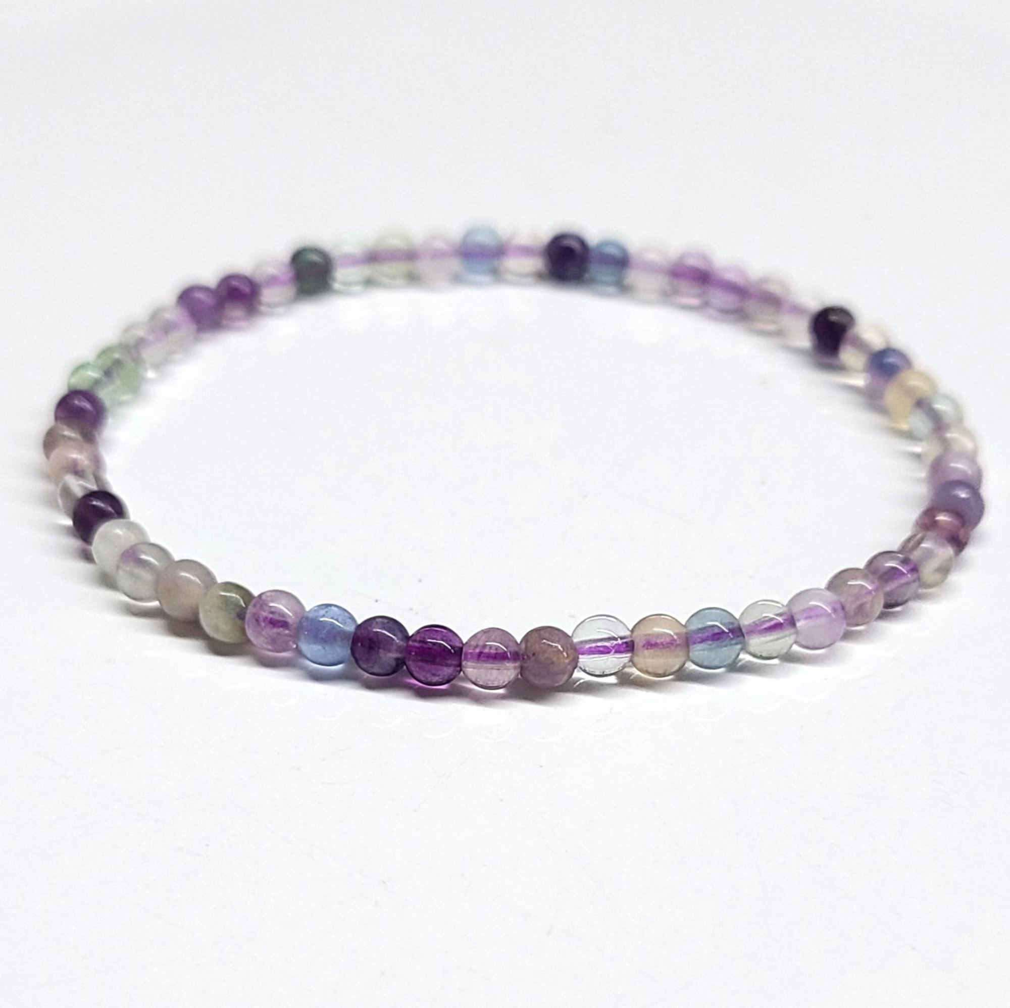 Fluorite bracelet with 4mm multicolored beads on white background.