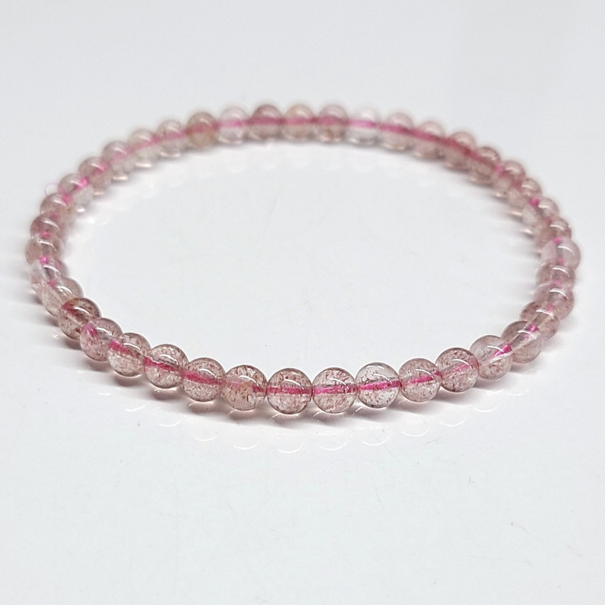 Strawberry Quartz Bracelet featuring delicate 4mm beads in pinkish-red hues, known for its aesthetic and metaphysical properties linked to love and healing.