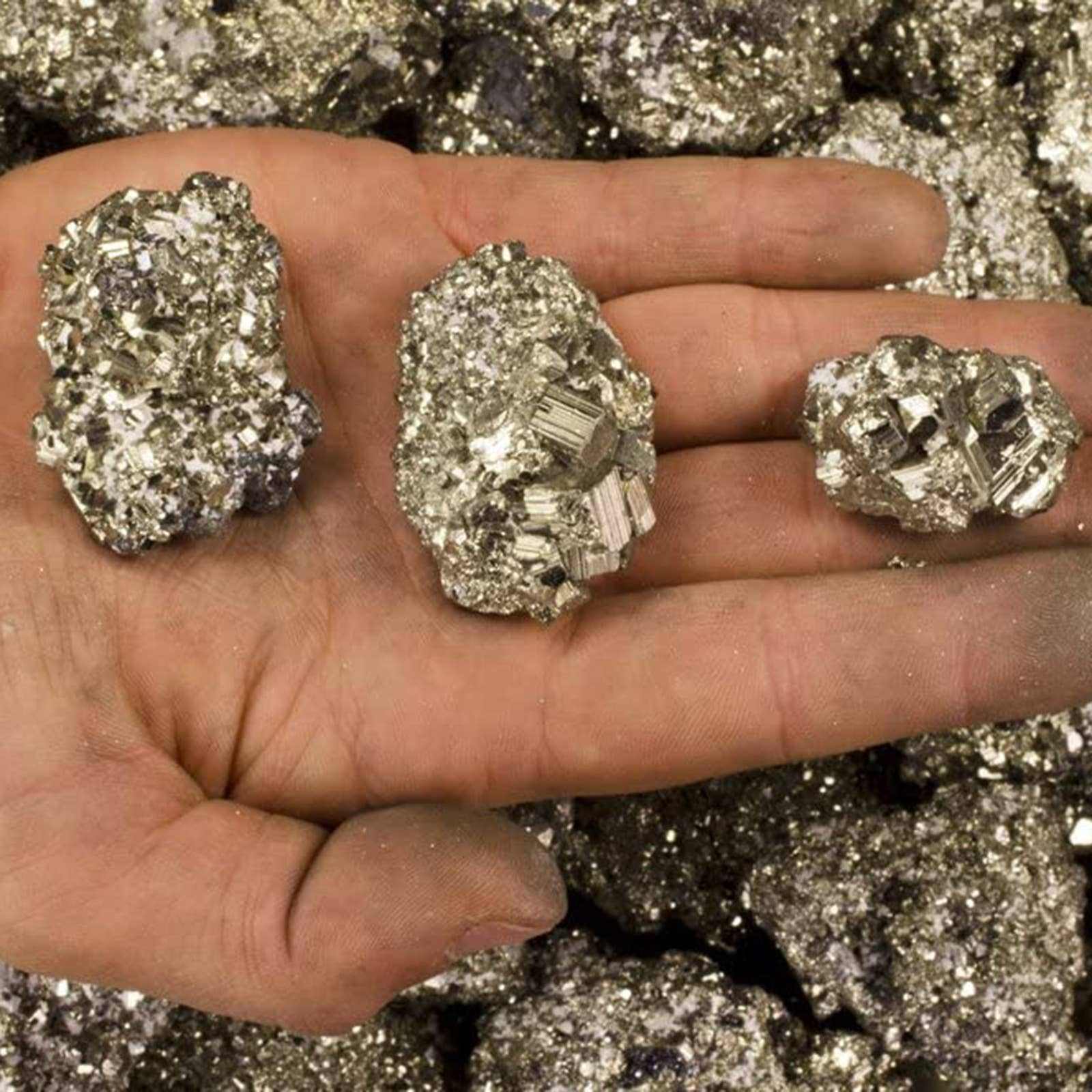 Three crystal rocks held in a hand with a background of more crystals.