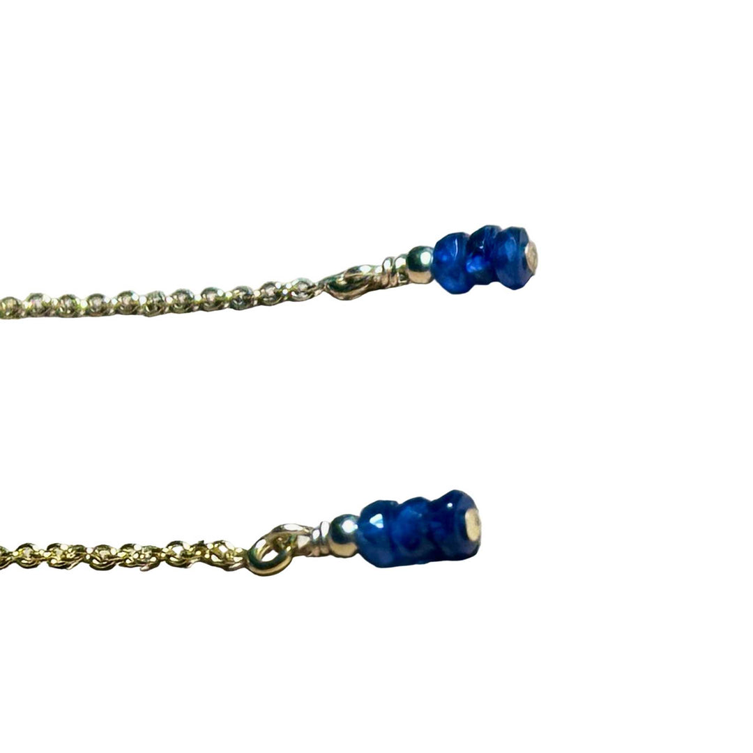Gold chain earrings with blue Sapphire beads on a background.