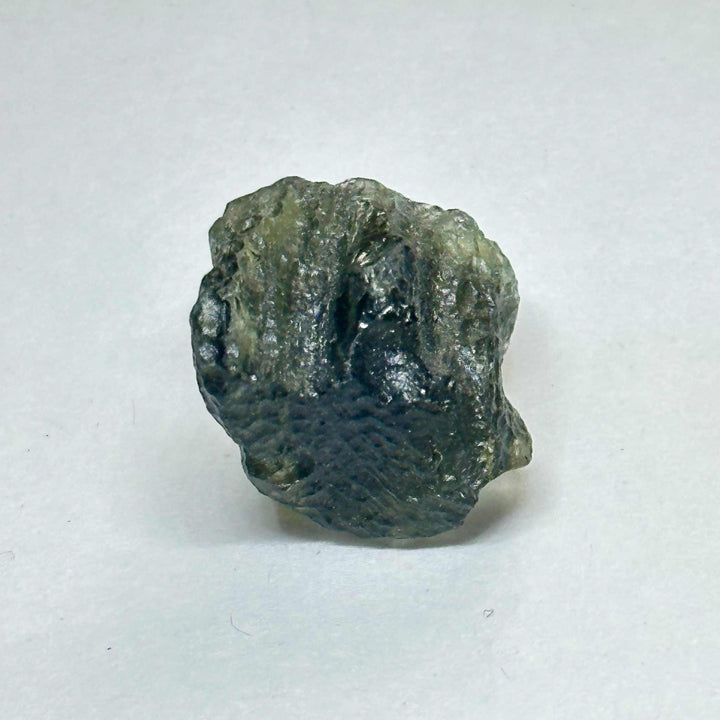 Moldavite tektite mineral weighing 4.243 grams with rough textured dark green surface on white background