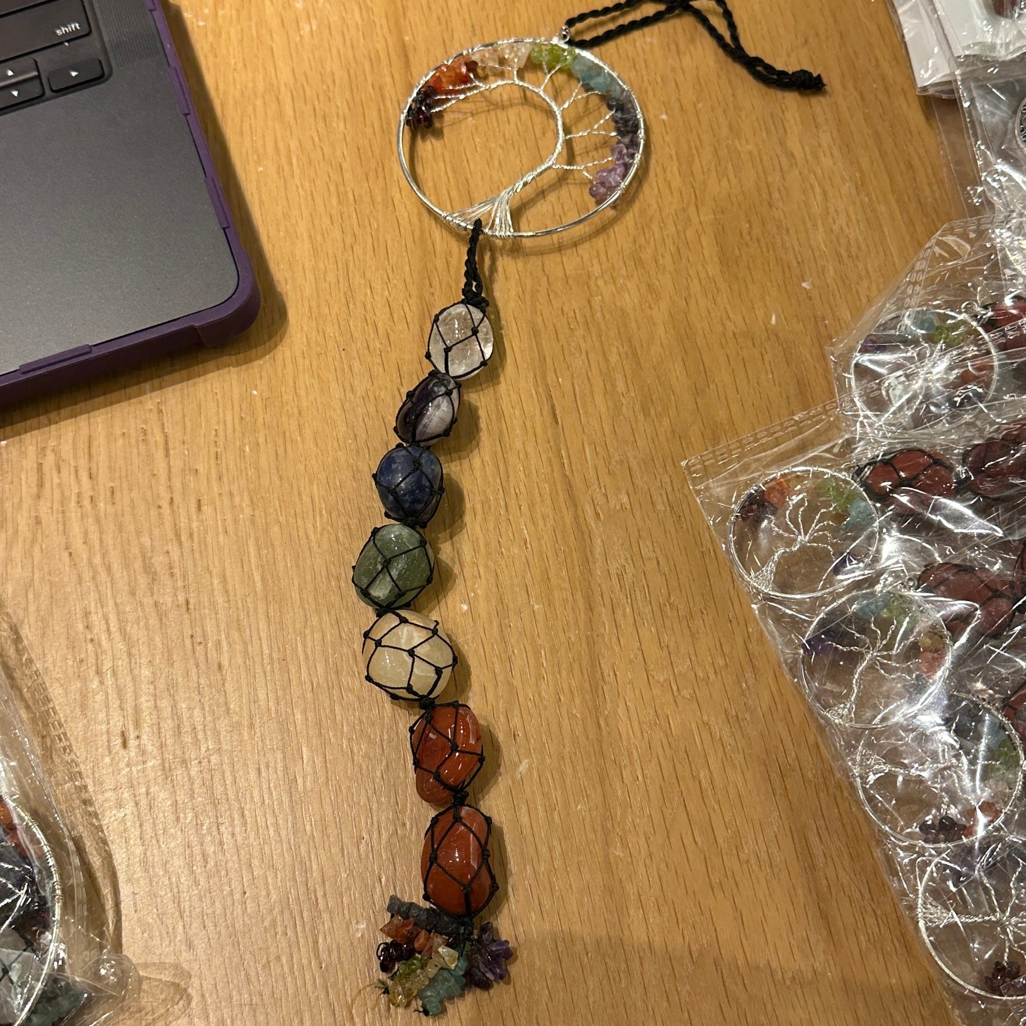 Tree Of Life Chakra Pride Hanging Ornament on wooden surface.