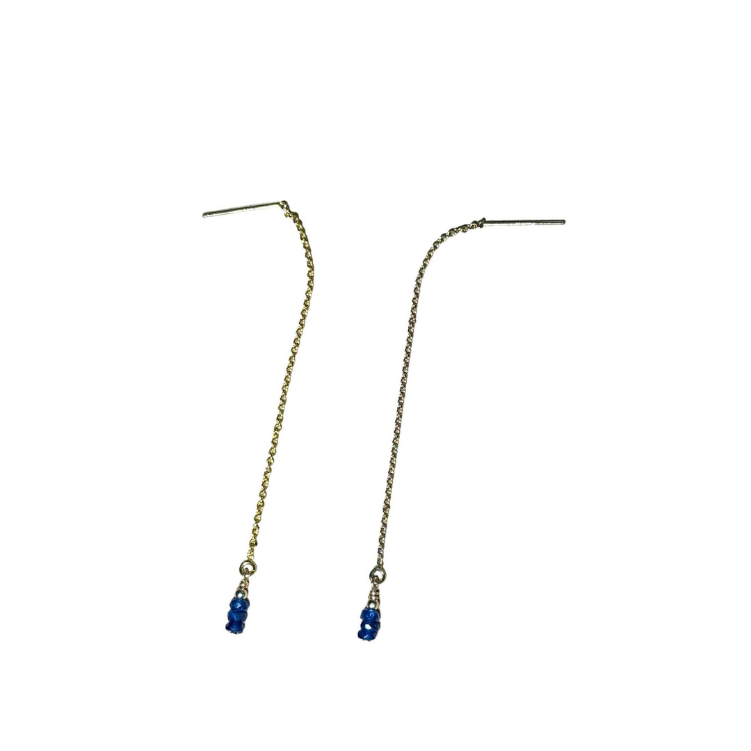 Gold chain earrings with blue Sapphire beads on a background.