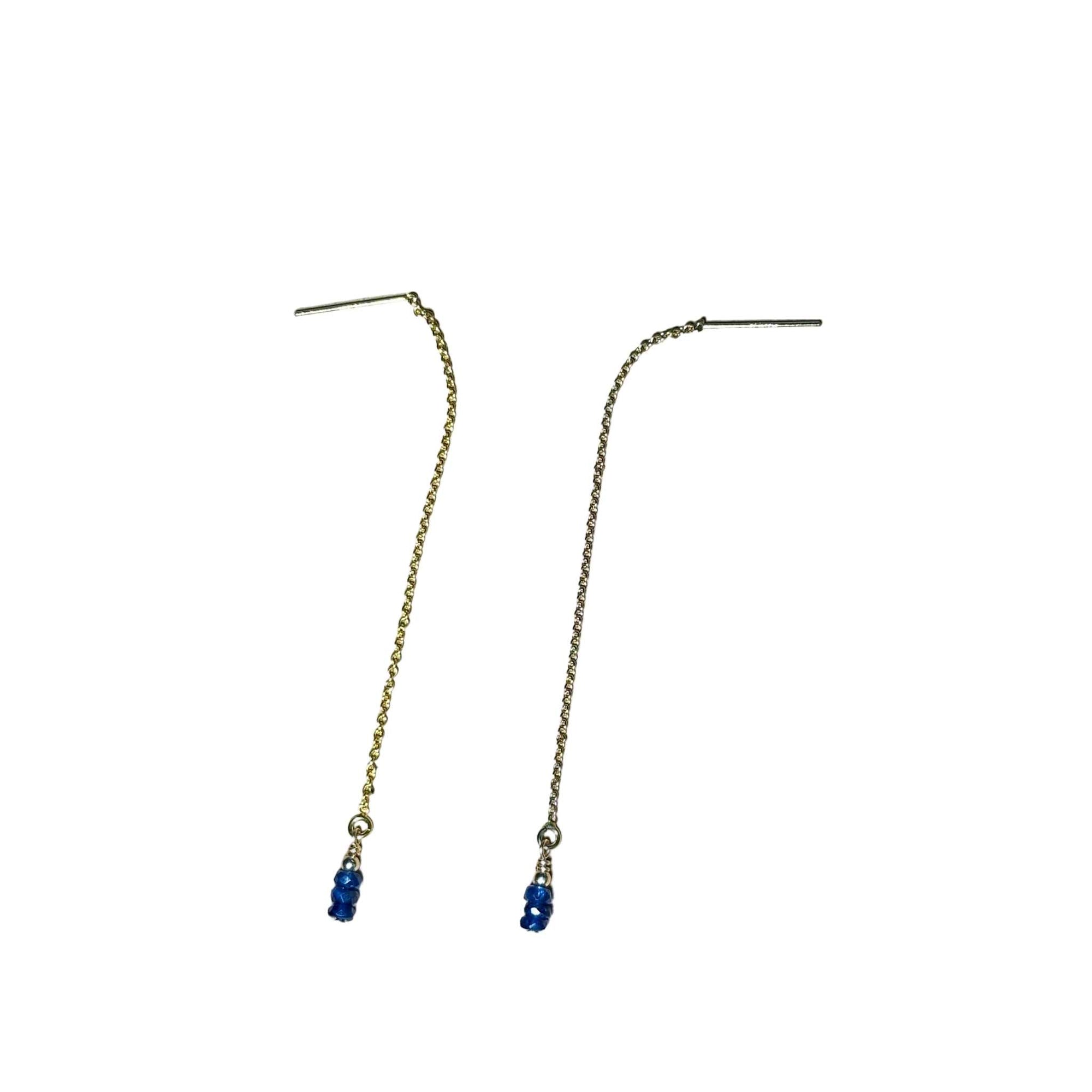 Gold chain earrings with blue Sapphire beads on a background.