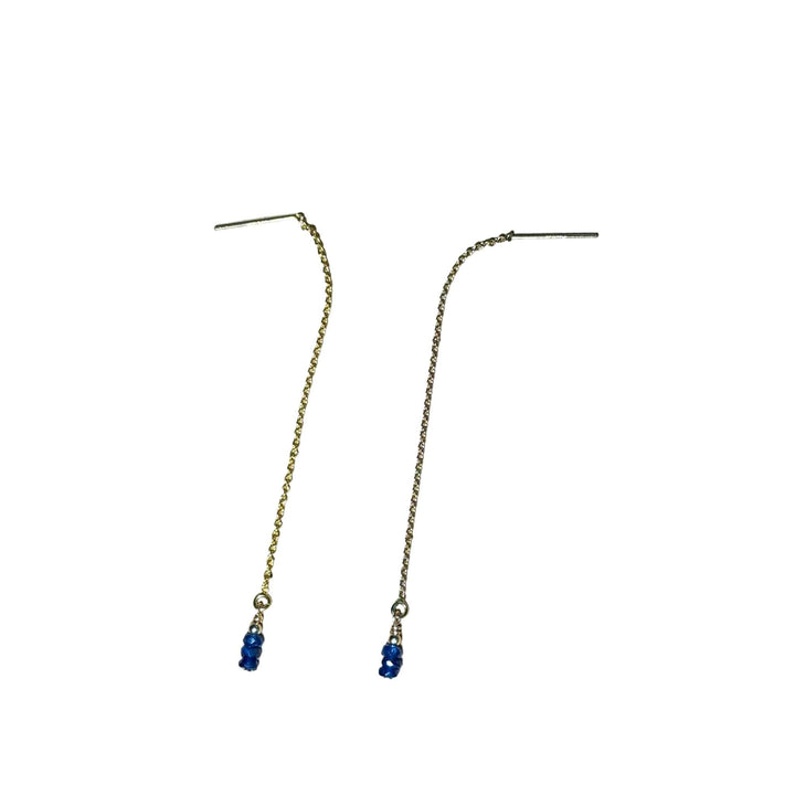 Gold chain earrings with blue Sapphire beads on a background.