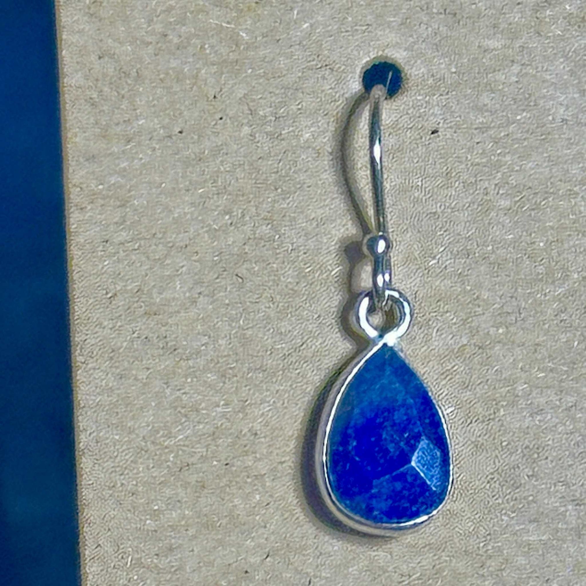 Blue Lapis Lazuli faceted teardrop earring in sterling silver setting on a background