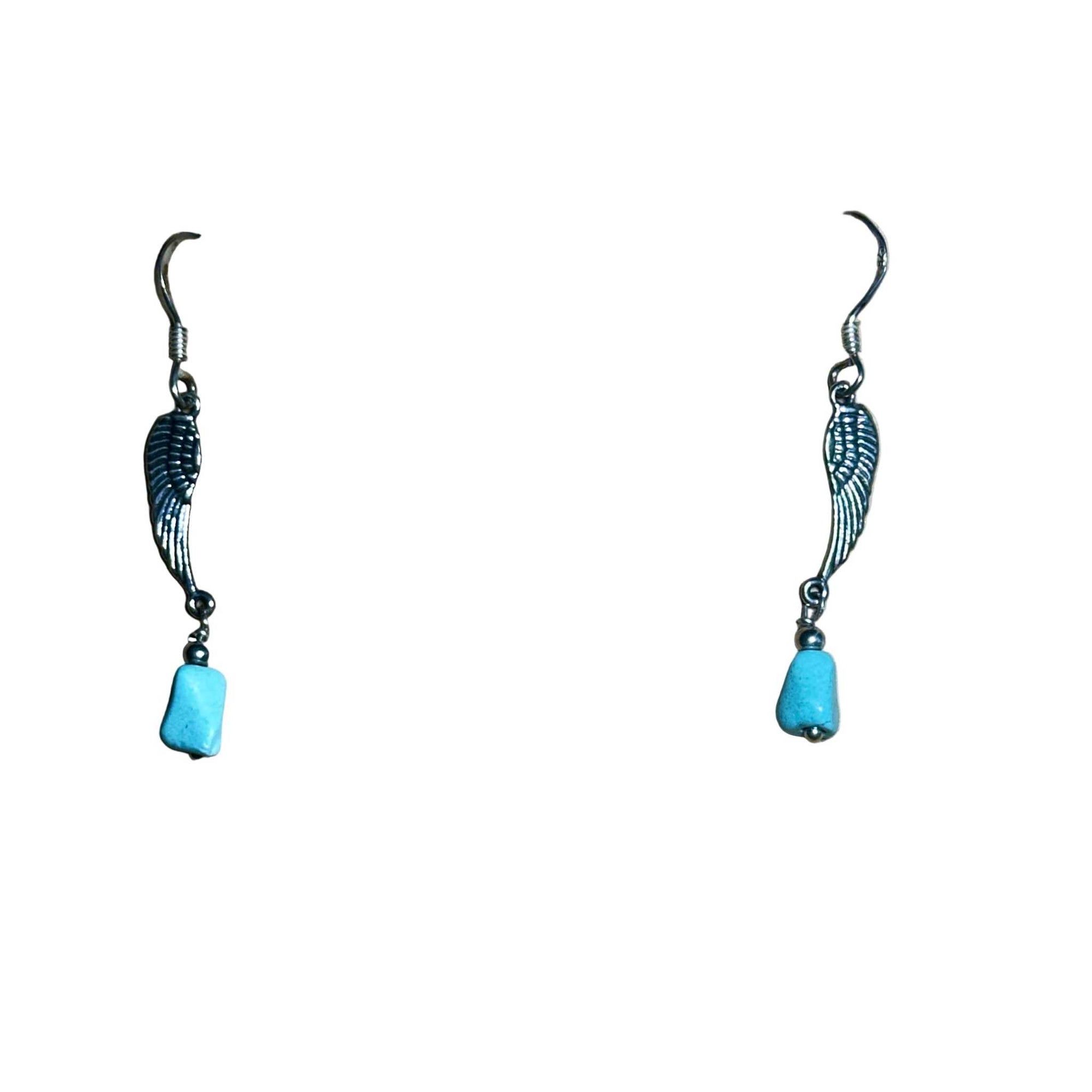 Pair of earrings with wing design and natural turquoise bead on a background