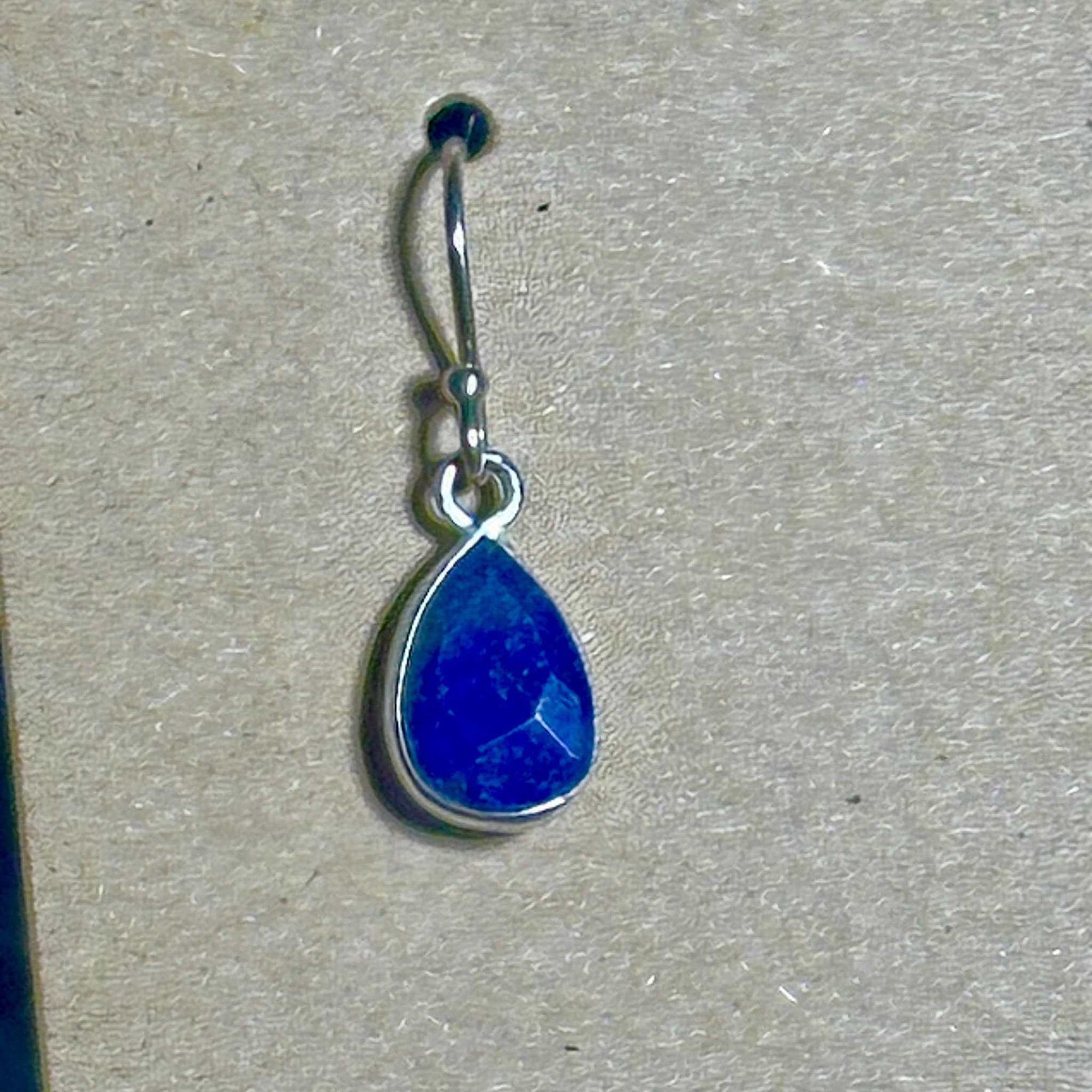 Blue Lapis Lazuli faceted teardrop earring in sterling silver setting on a background