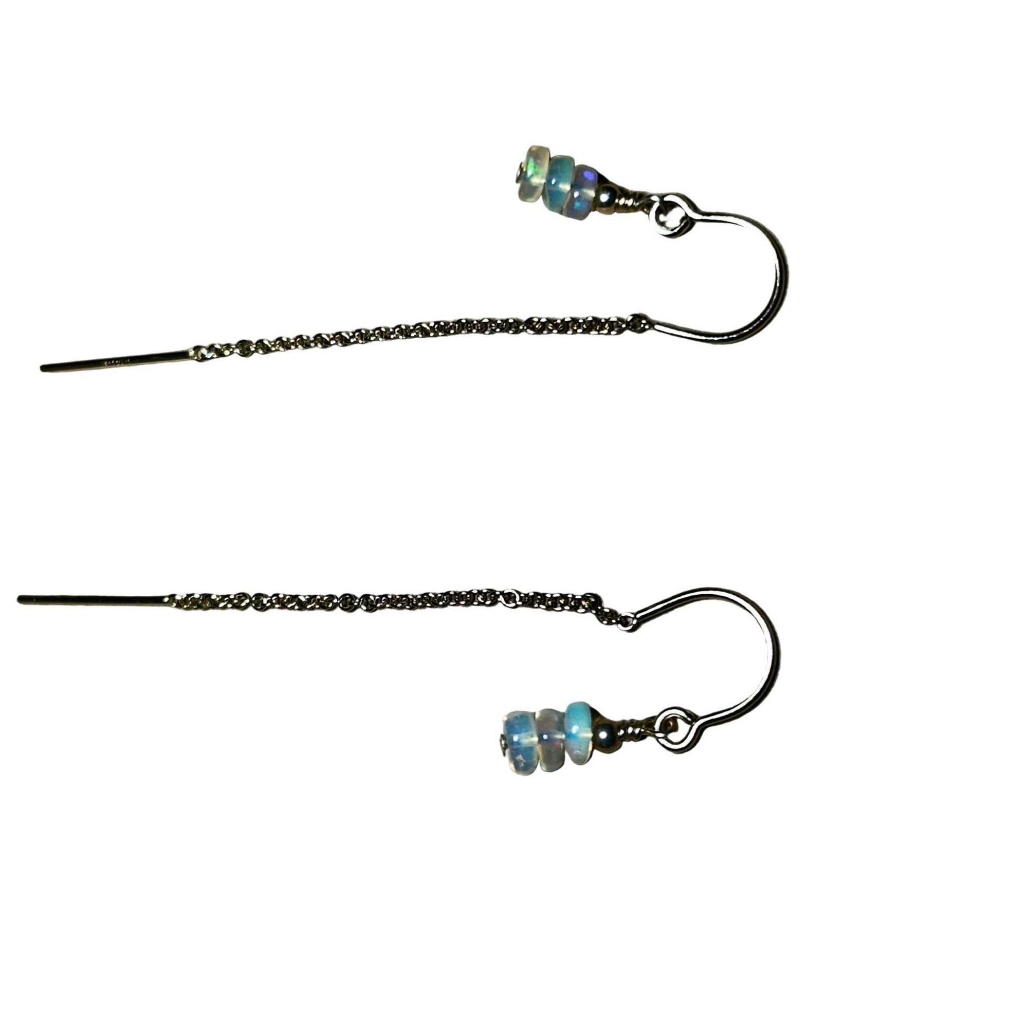 Pair of gold chain earrings with beaded Opals on a surface