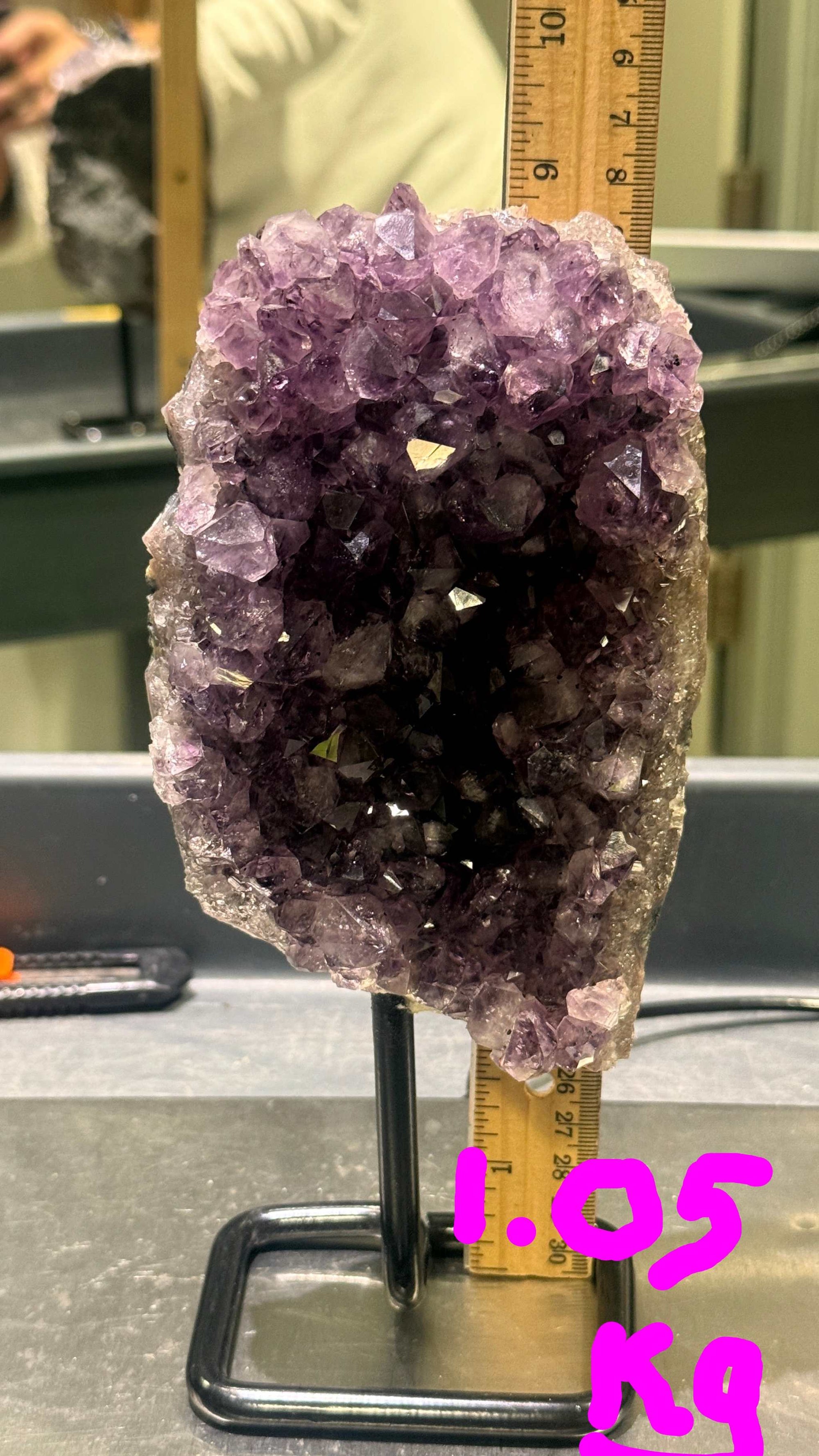 Amethyst crystal formation with a ruler for scale on a metallic surface