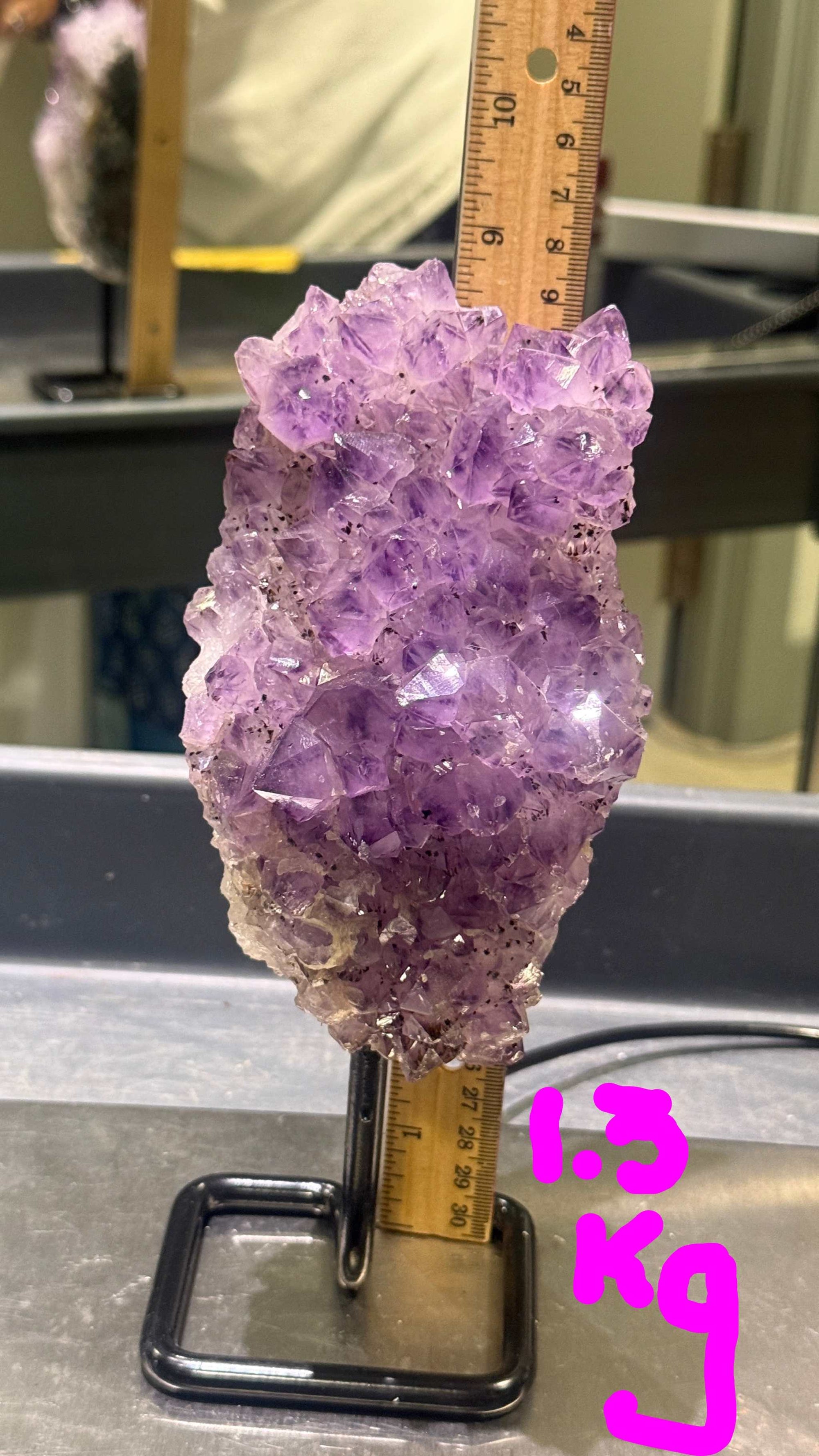 Amethyst crystal with a ruler for scale on a metallic surface