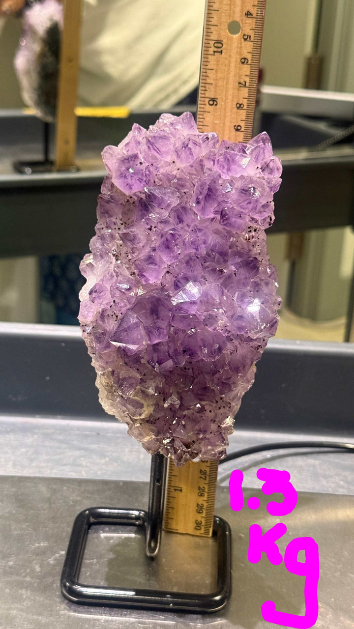 Amethyst crystal with a ruler for scale on a metallic surface