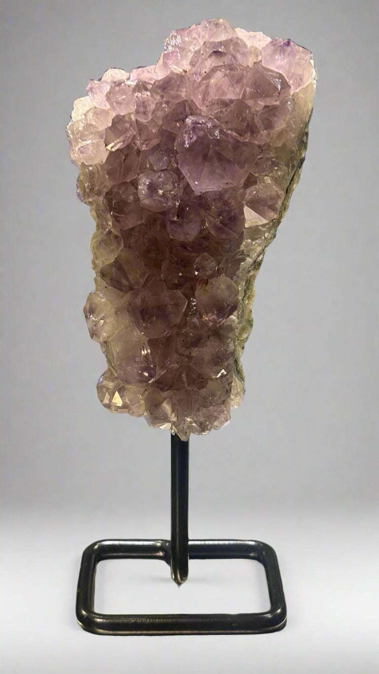 Amethyst crystal on a stand against a neutral background