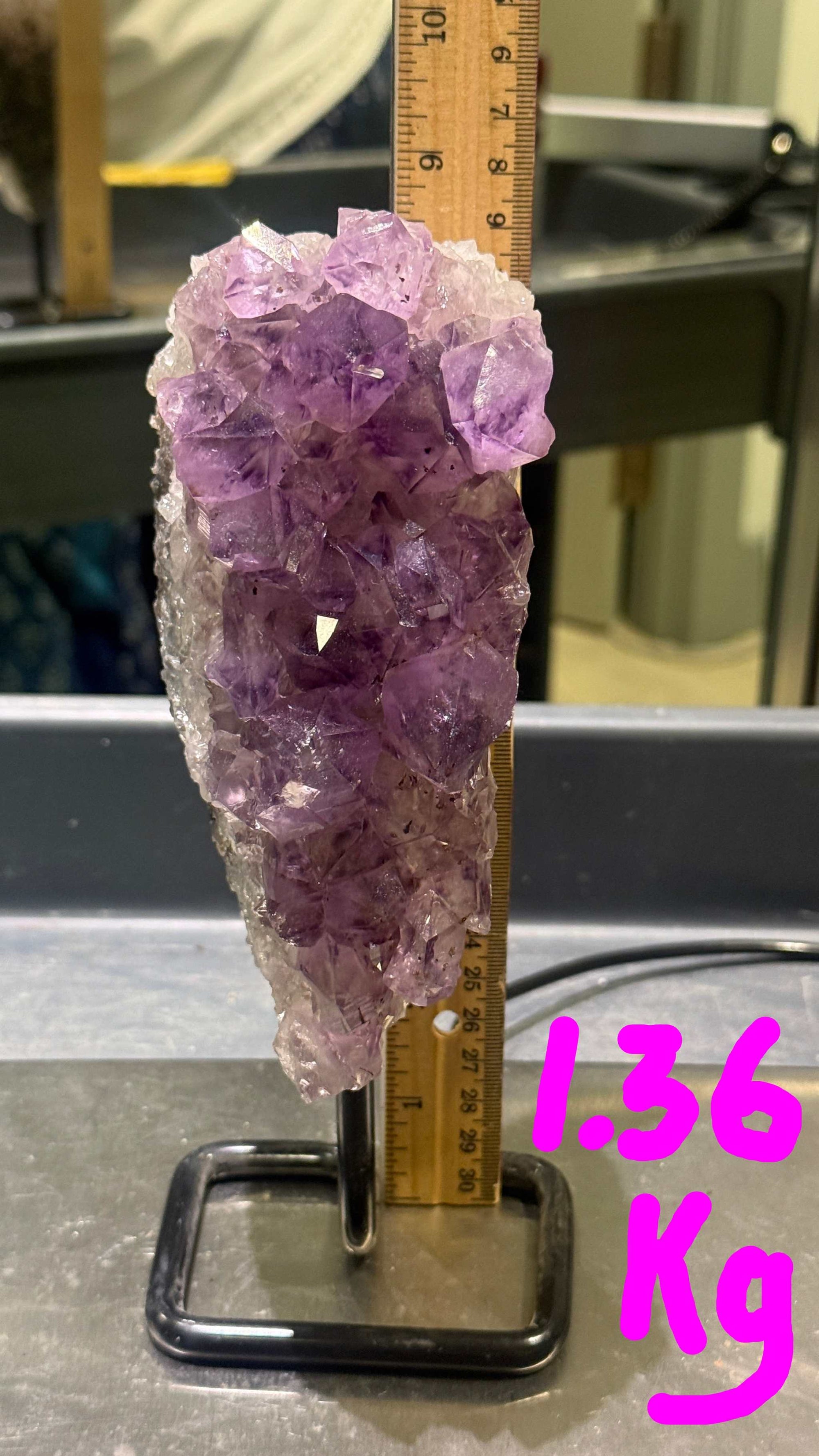 Amethyst crystal cluster with a ruler for scale on a dark surface