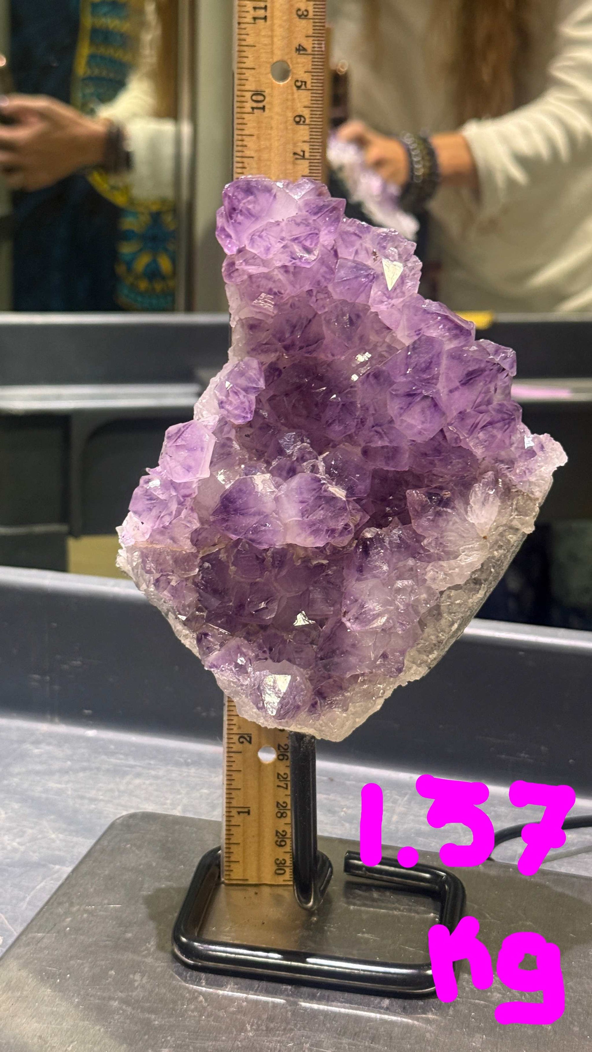 Amethyst crystal on a stand with a ruler for scale