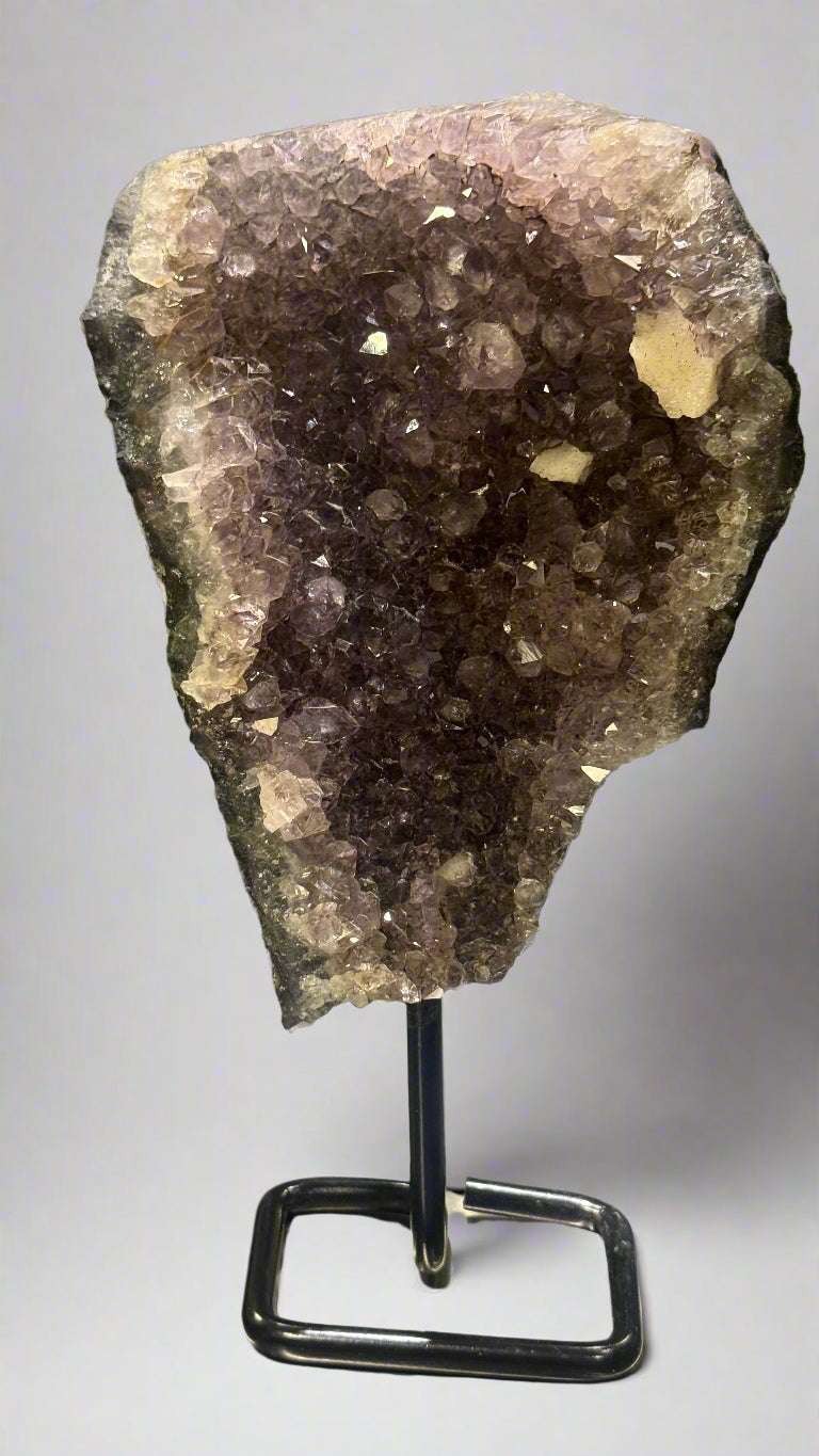 Amethyst crystal on a stand against a neutral background