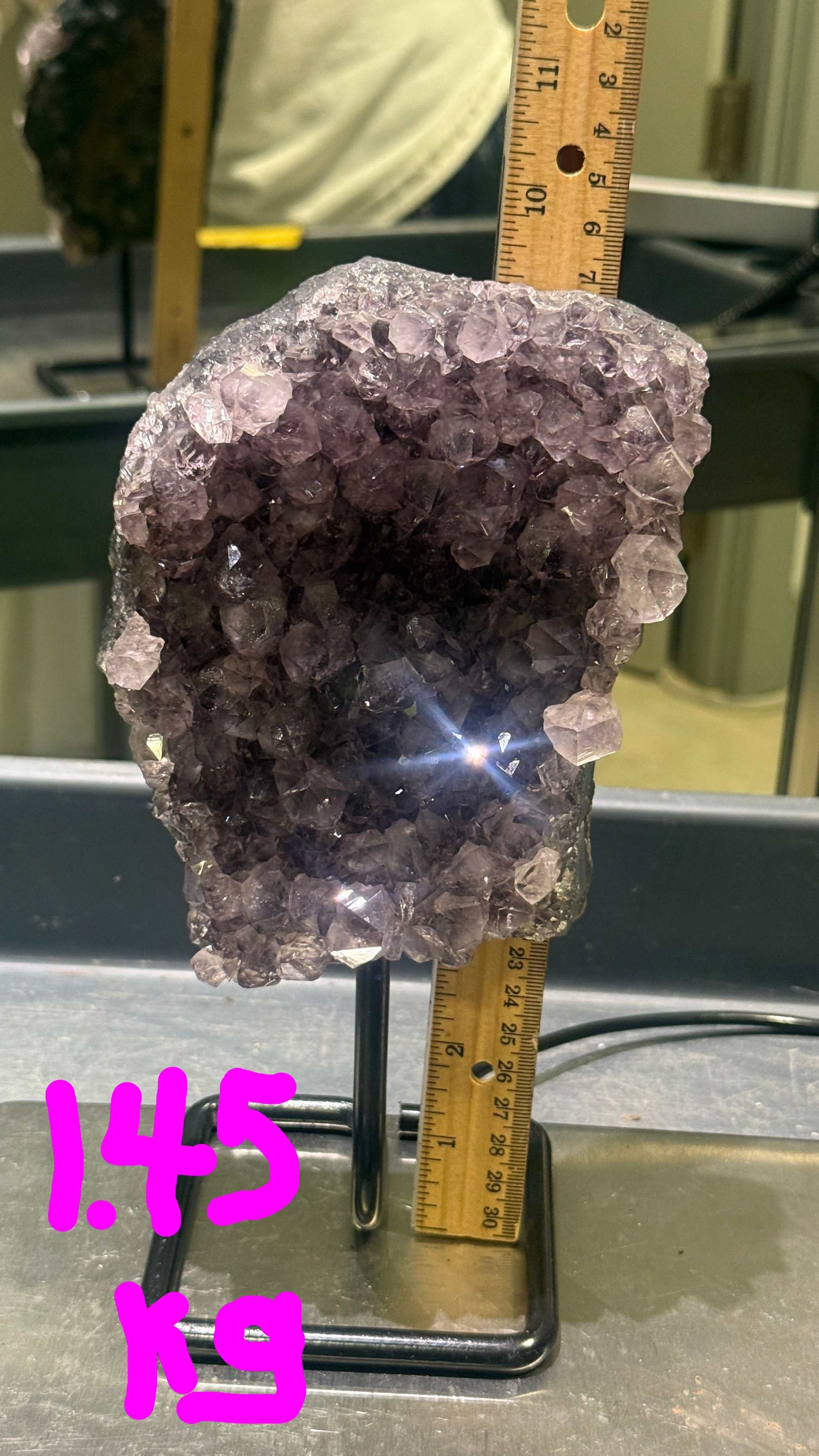 Amethyst crystal geode with a ruler for scale on a metal surface