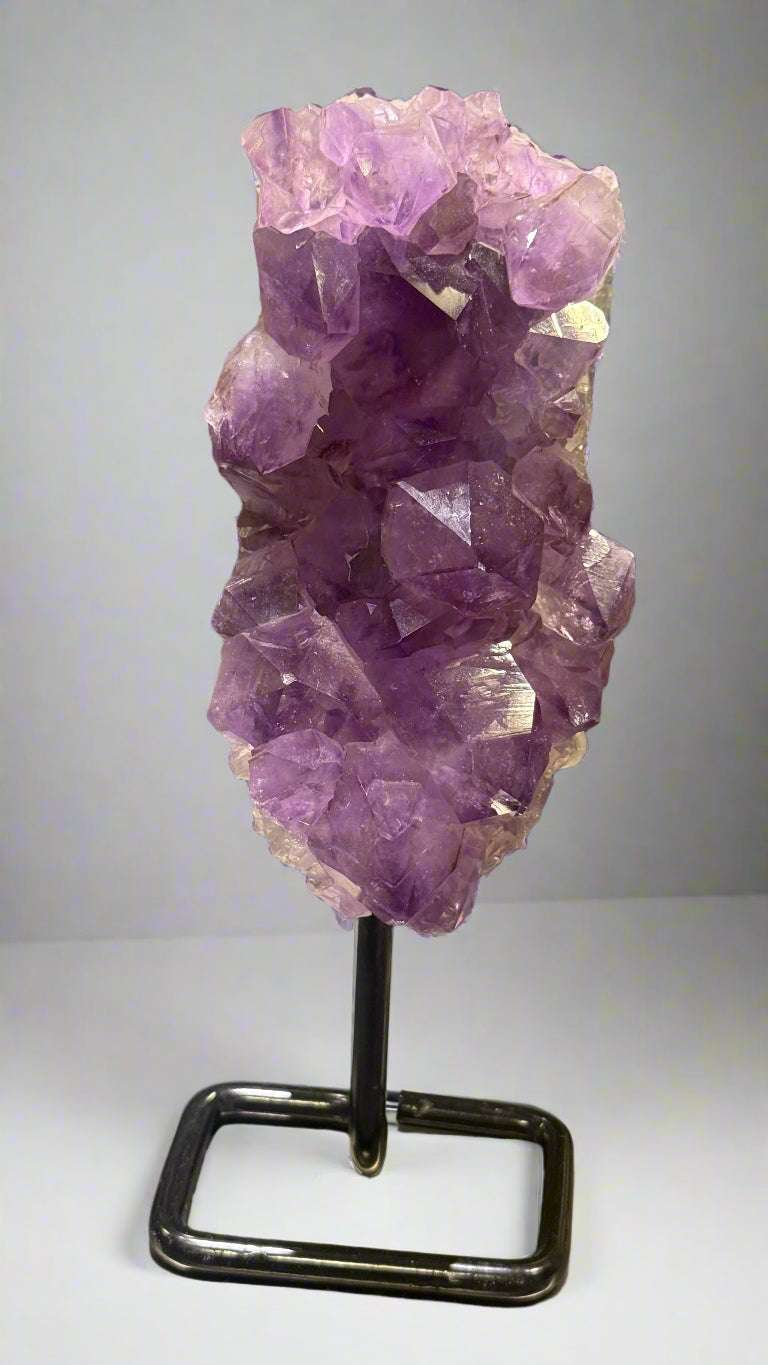 Purple crystal cluster on a stand with a blurred background