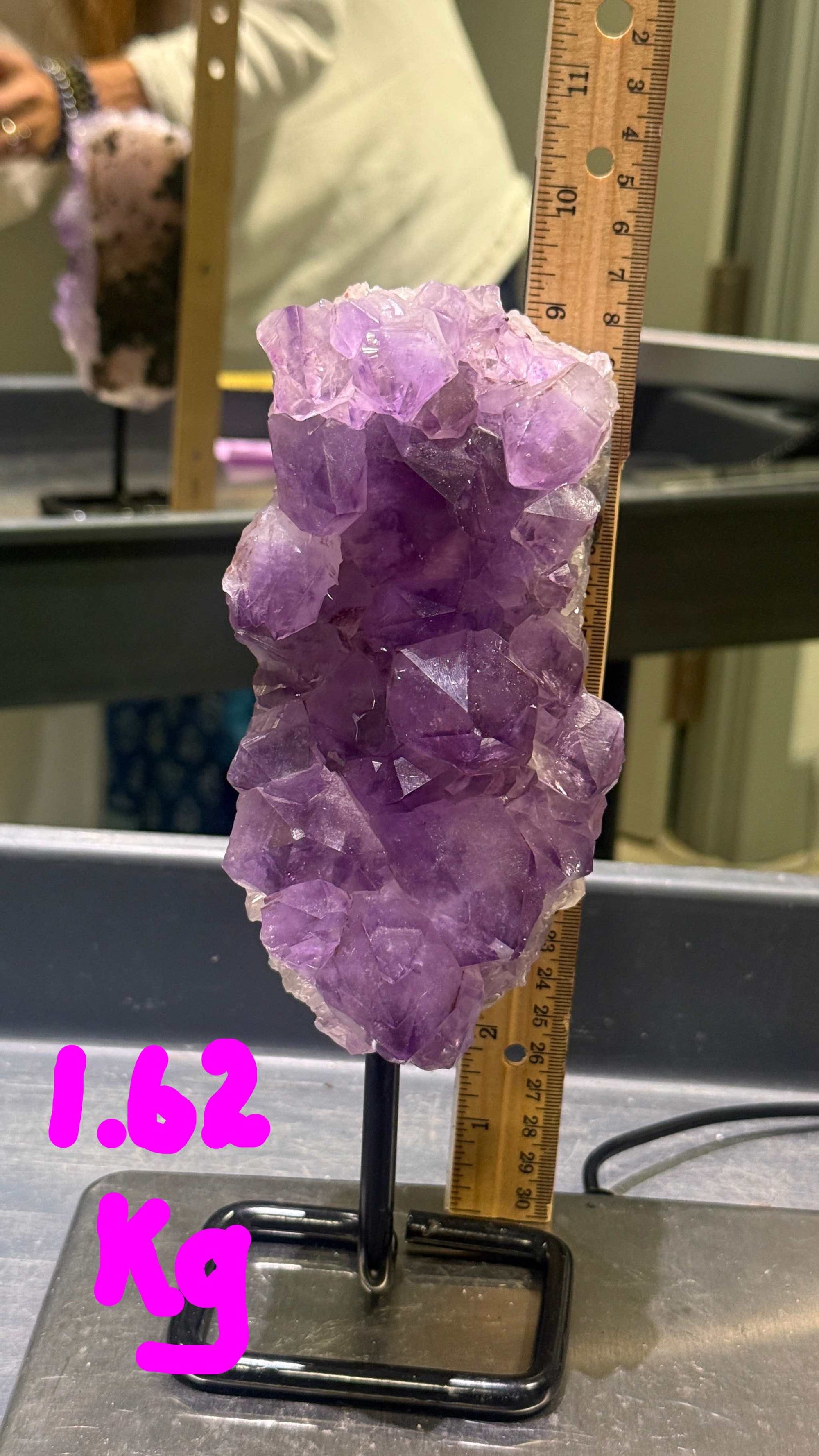 Amethyst crystal on a stand with a ruler for scale