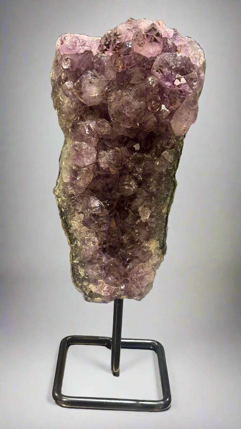 Amethyst crystal on a stand against a neutral background