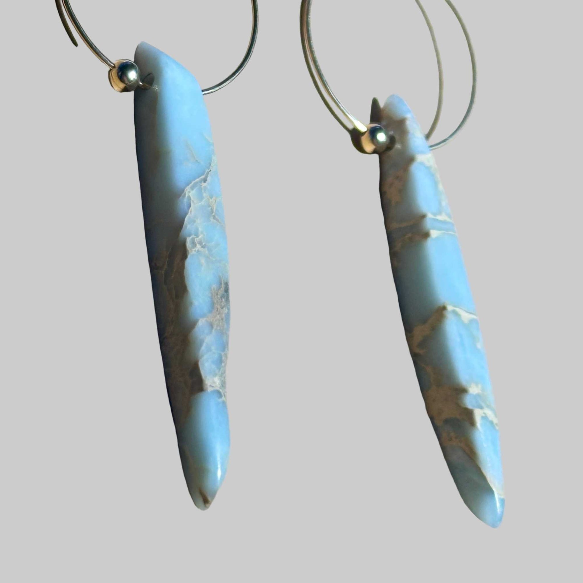 Gold Hoop earrings with blue marbled African Opal stone pendant on a background