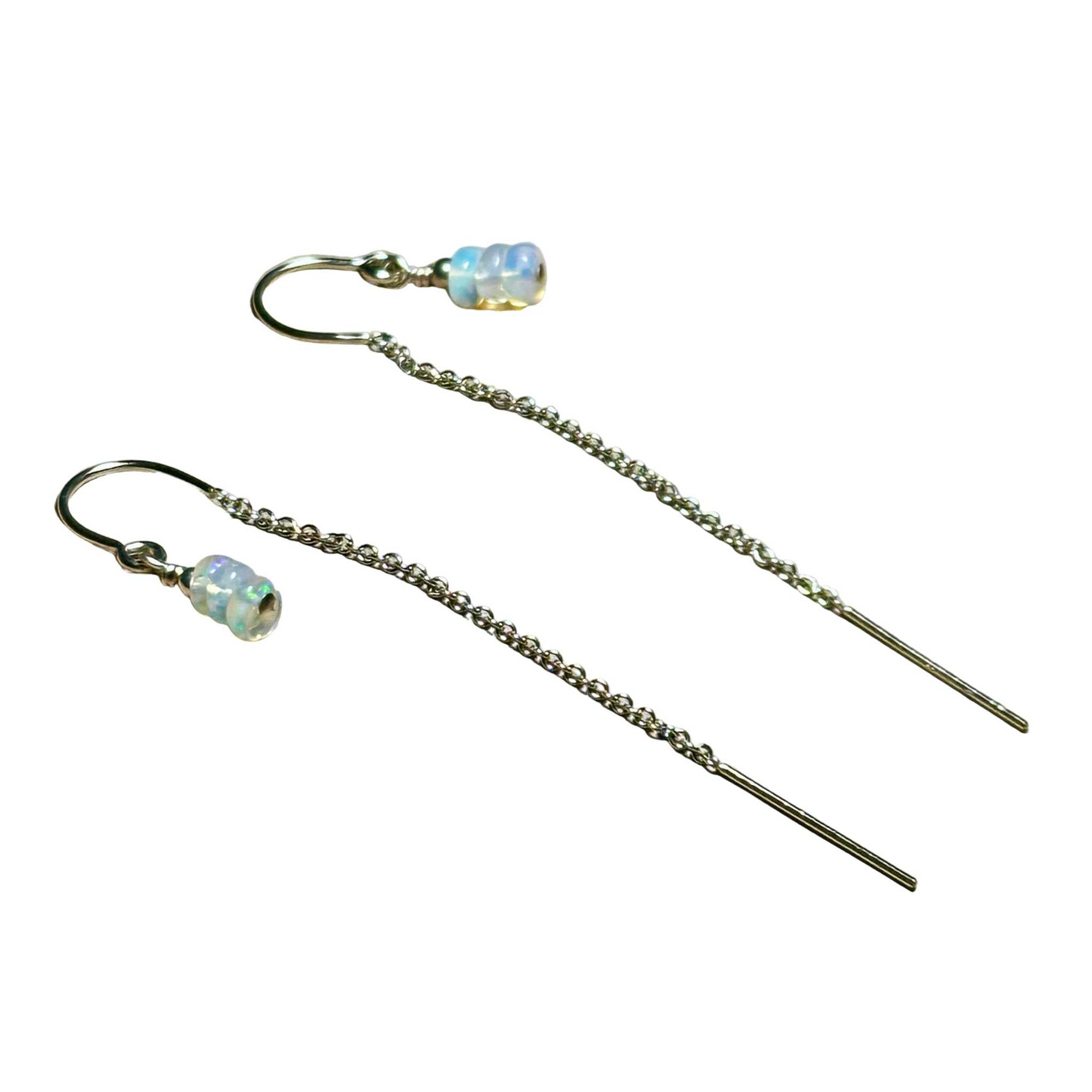 Pair of gold chain earrings with beaded Opals on a surface