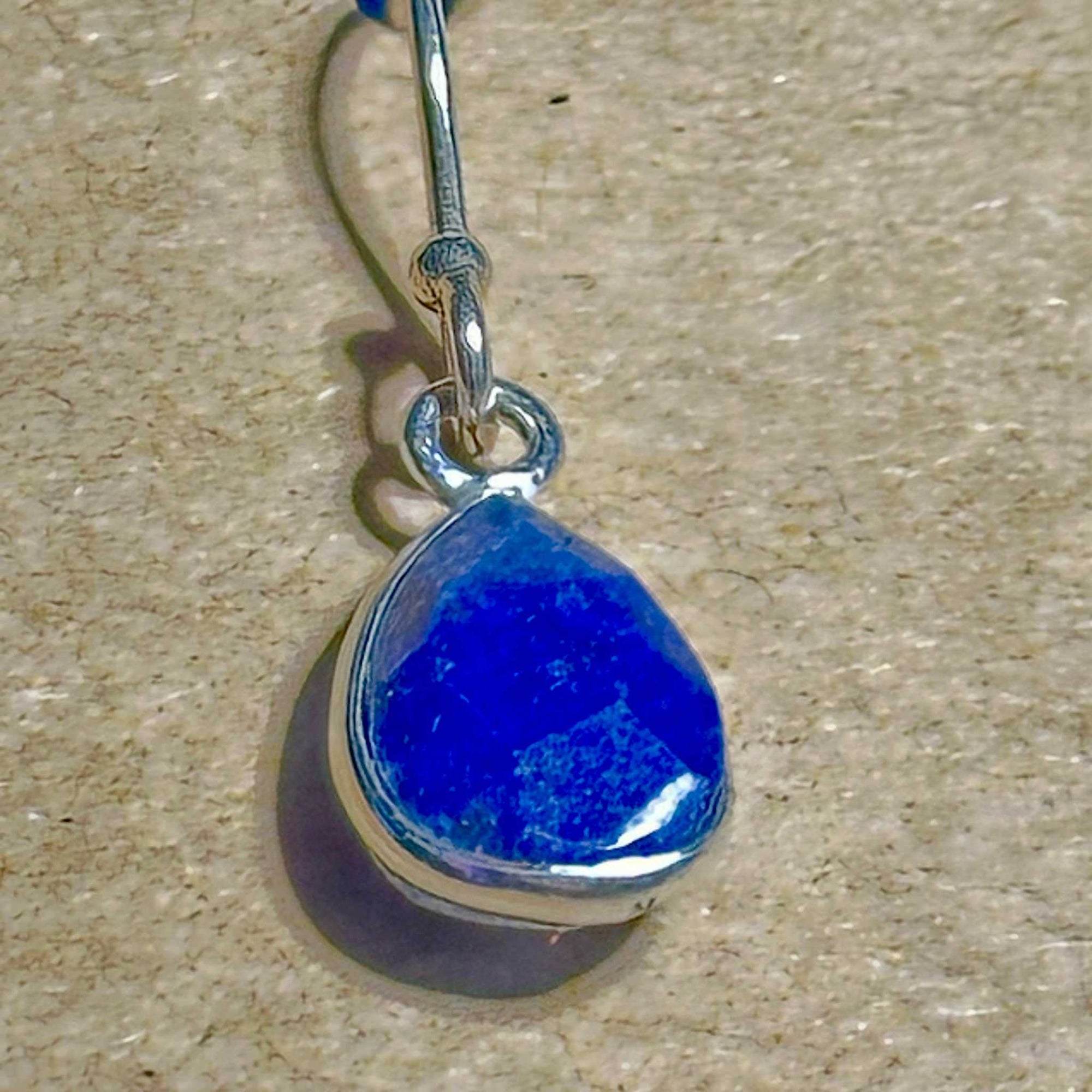 Blue Lapis Lazuli faceted teardrop earring in sterling silver setting on a background