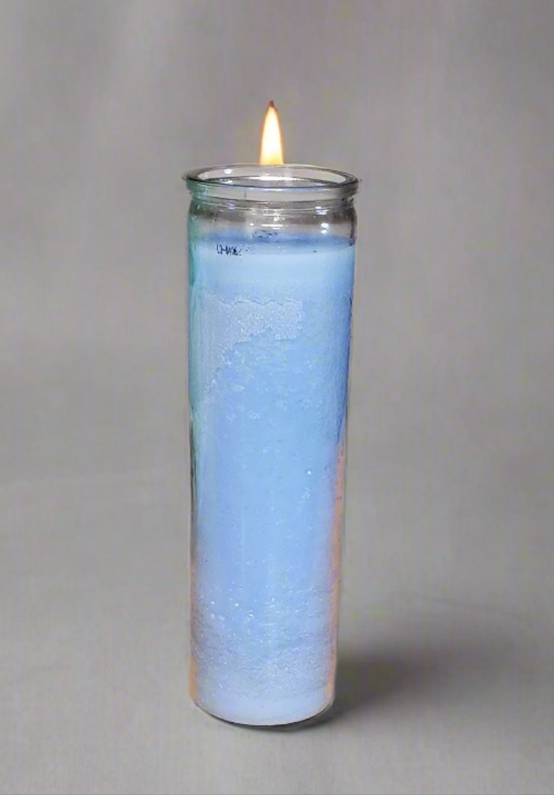 Lit blue 7 day jar candle in clear glass container on neutral background