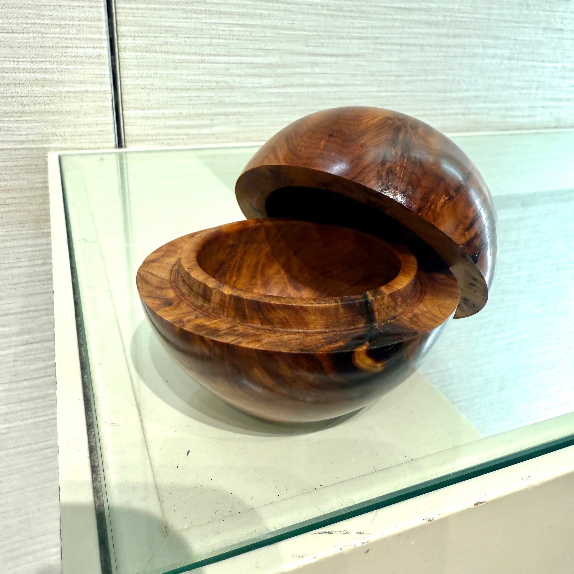 Thuya Wood Globe Box with distinctive grain patterns on a glass shelf.