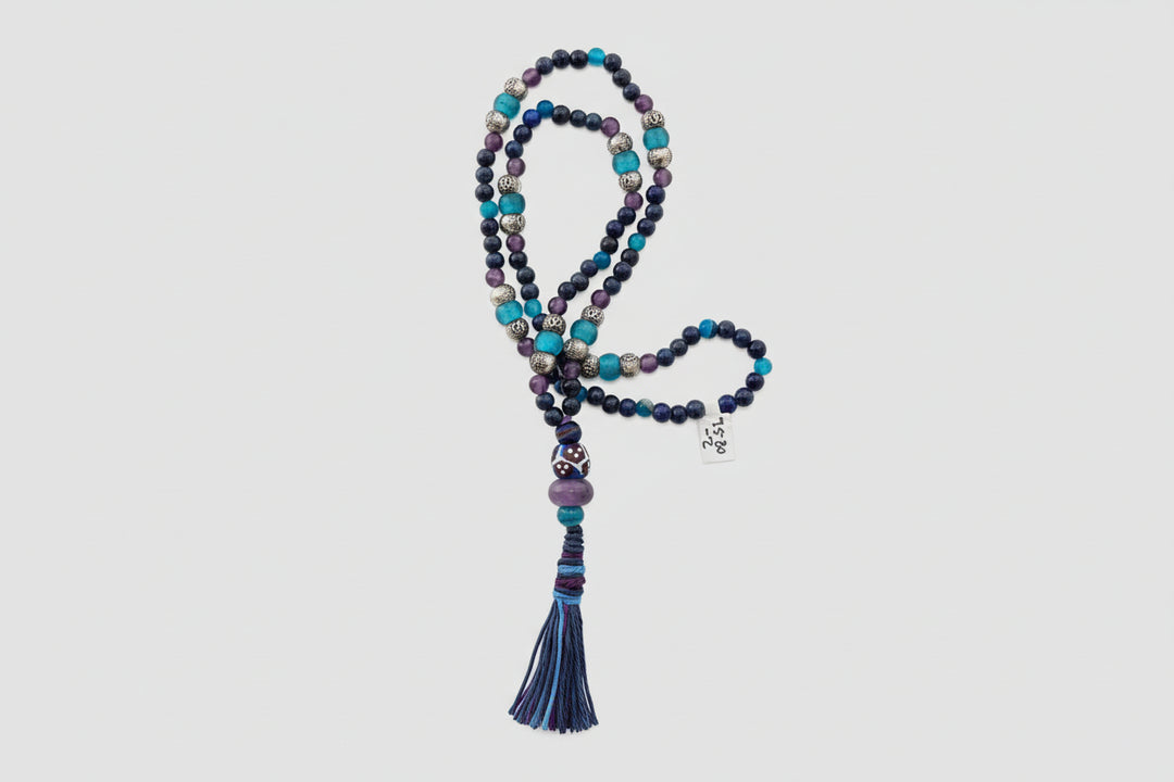 Multicolored beaded necklace with tassel on a decorative stone surface