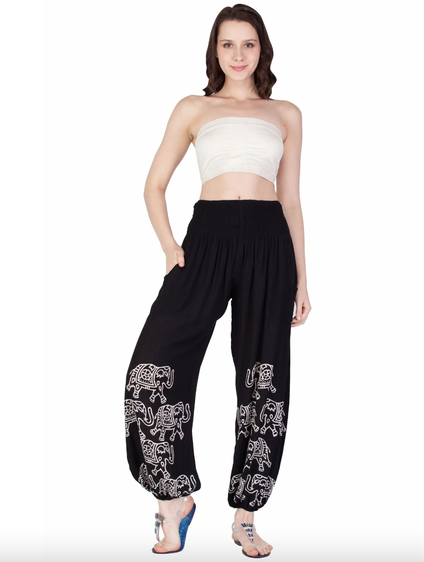 Woman wearing black harem pants with white elephant prints and elastic waistband and cuffs.