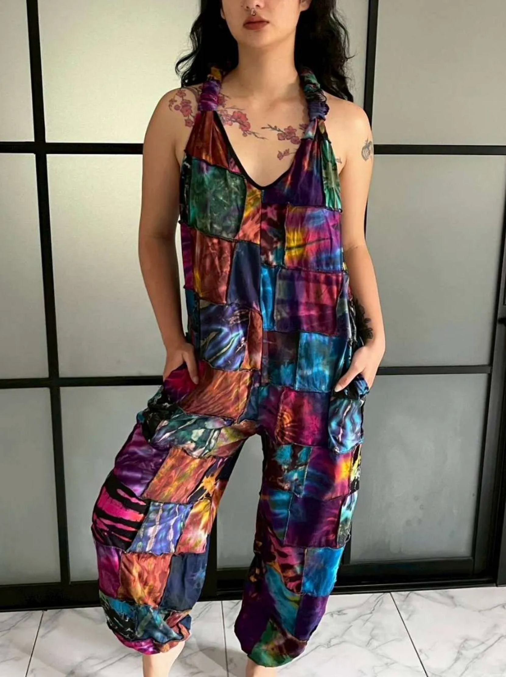 Woman wearing a vibrant boho patchwork cotton jumpsuit with unique multicolored patch designs and a relaxed fit.