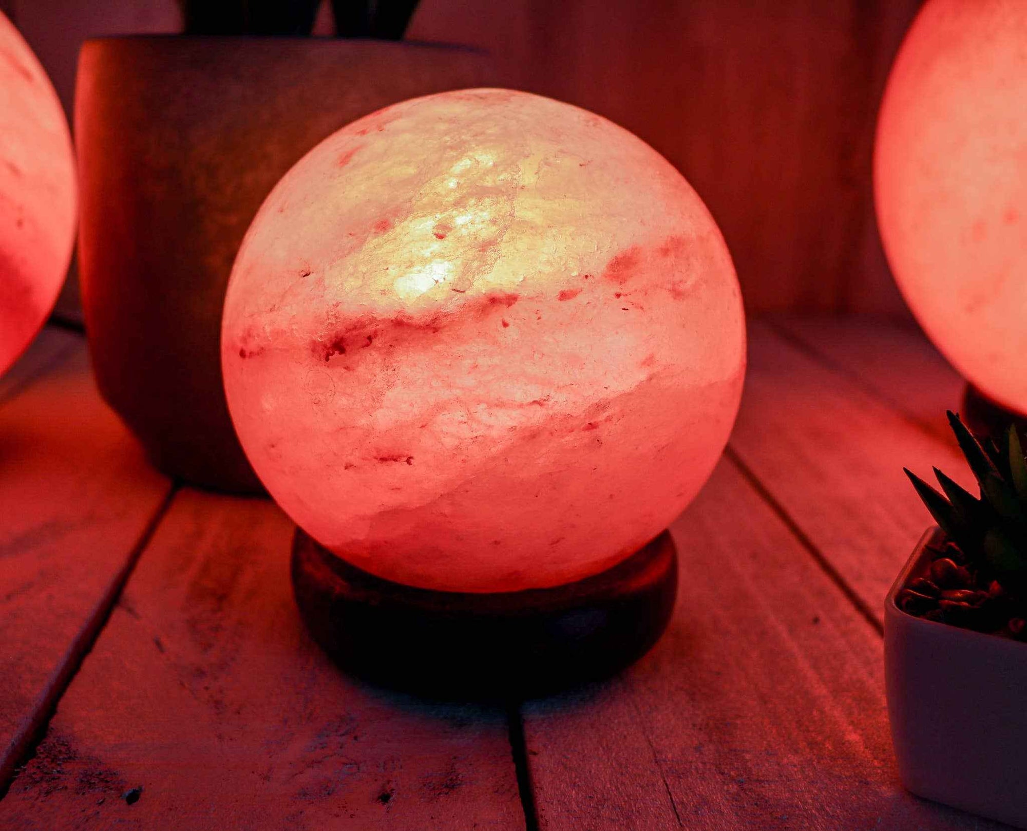Mini globe shape salt lamp glowing softly on wooden surface with warm pink Himalayan salt tones