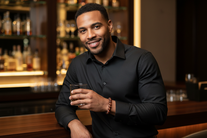 Goldstone bracelet hero - mixed-race man at sleek bar, copper flecks catching light