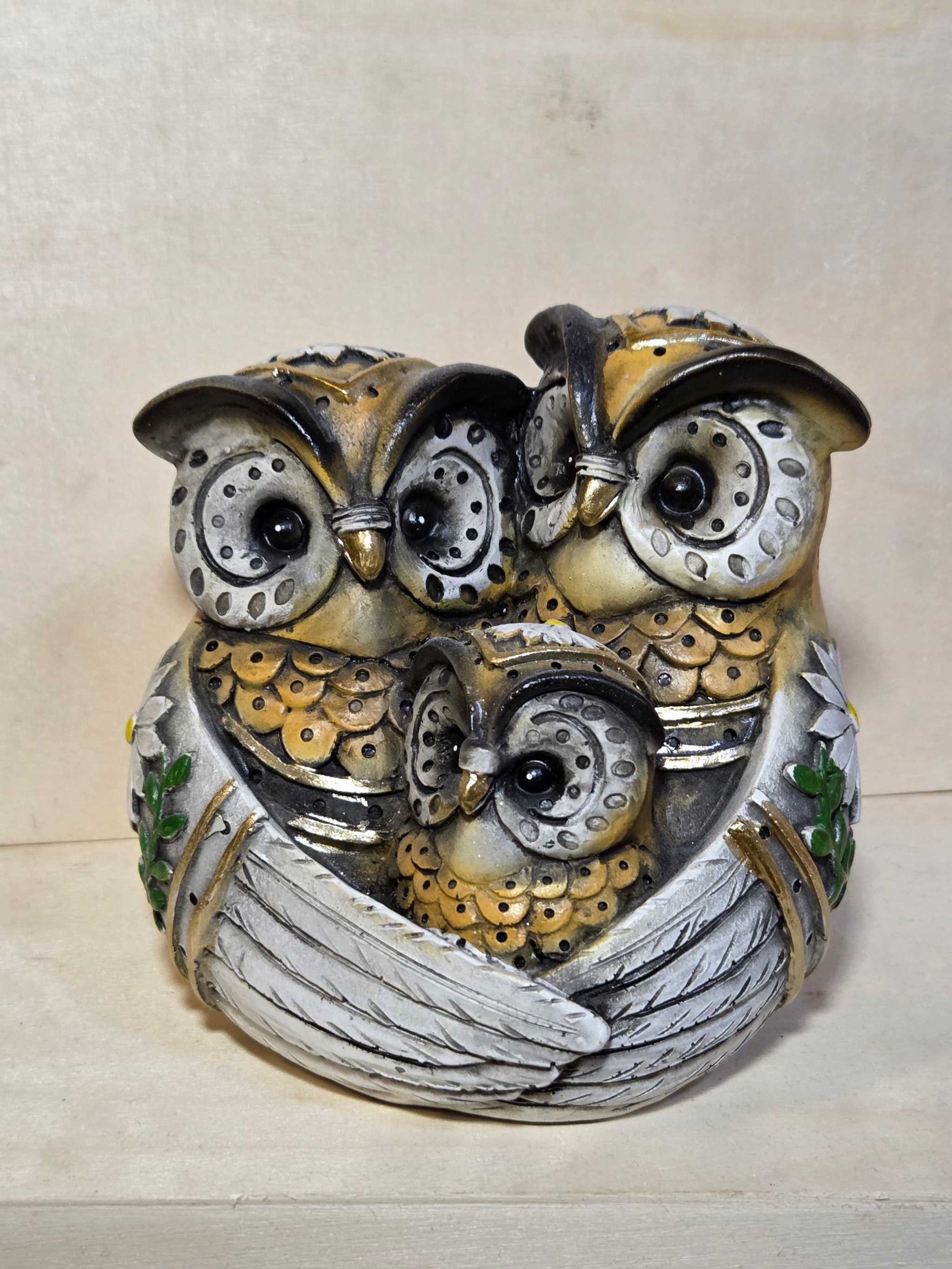 Decorative owl sculpture with metallic accents on a wooden surface