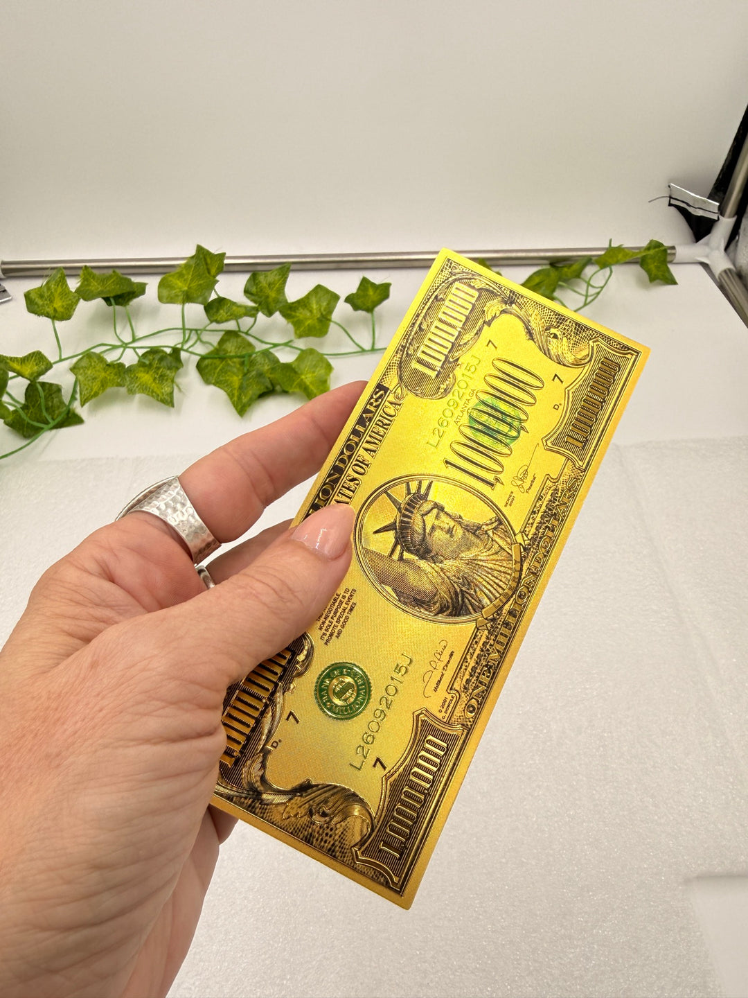 Gold million dollar bill held in hand for scale