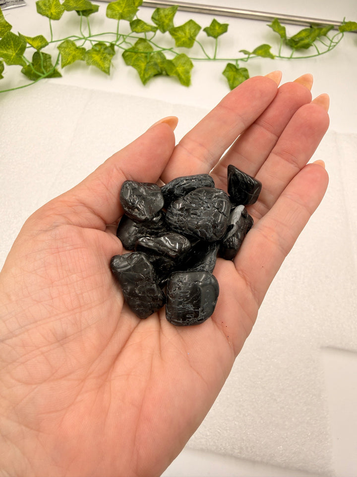 Black tourmaline tumbled stones held in hand