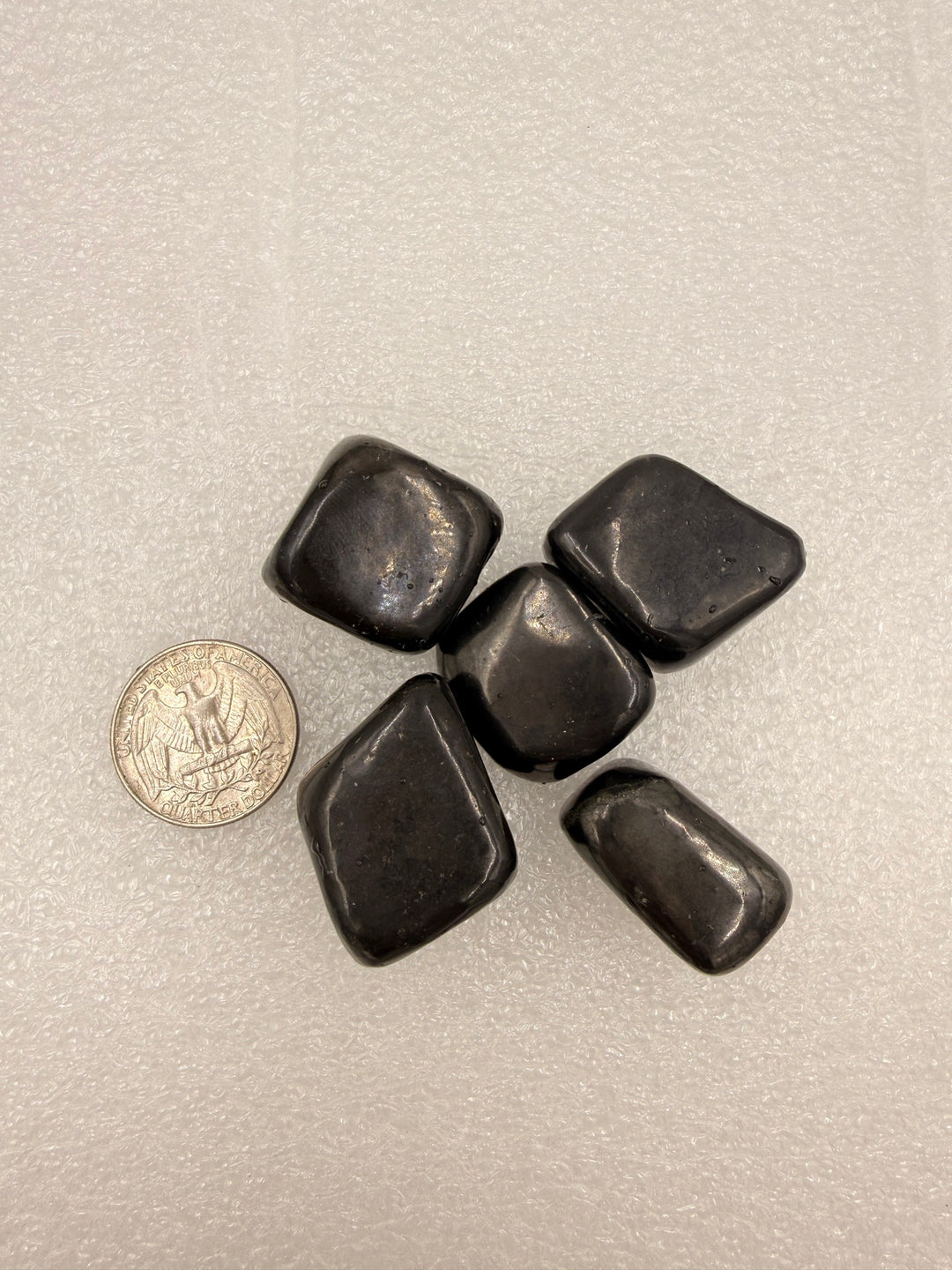 Shungite tumbled stones with a quarter for scale