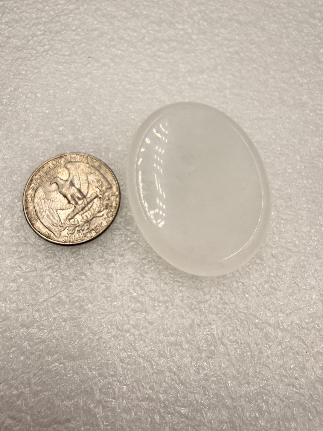 Clear quartz comfort stone with a quarter for scale
