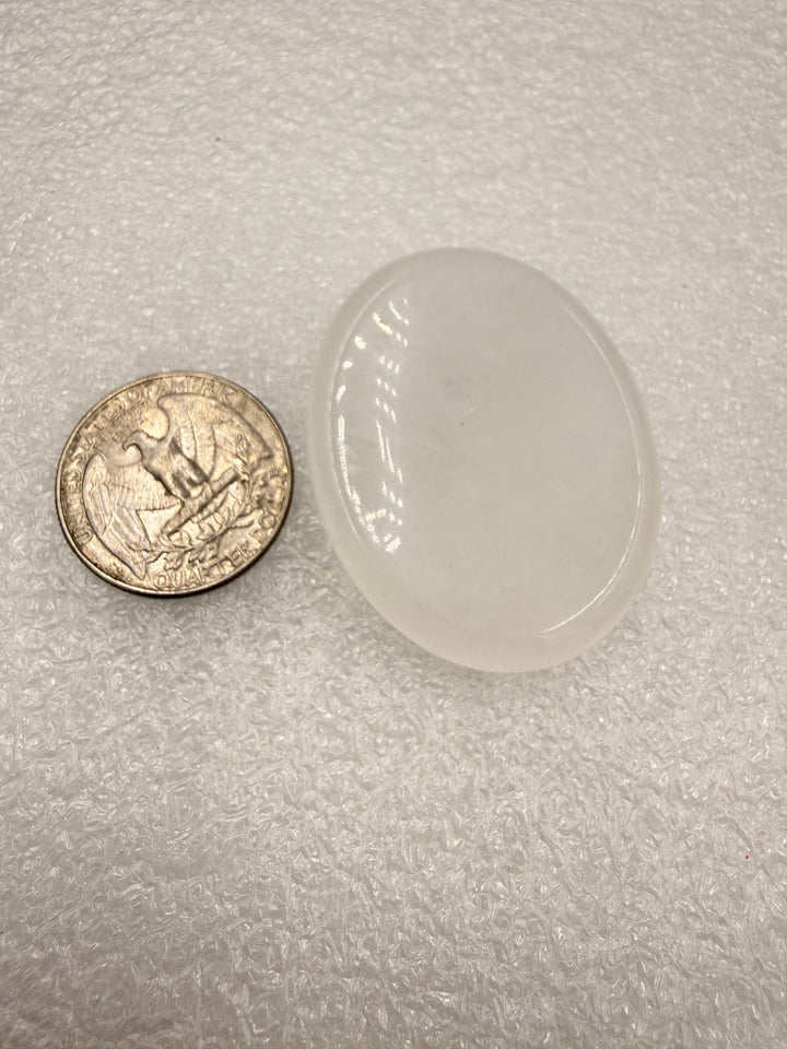 Clear quartz comfort stone with a quarter for scale