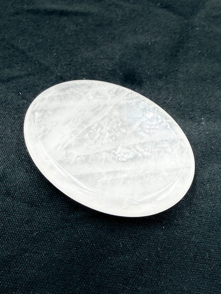 Clear quartz comfort stone on dark cloth, angled view