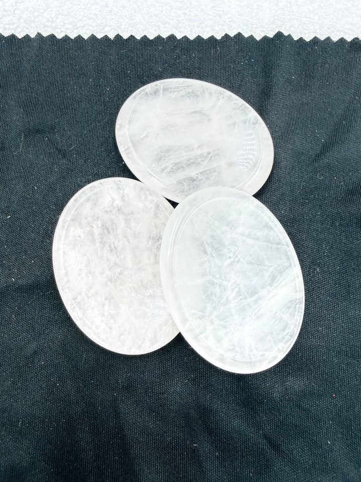 Three clear quartz comfort stones on dark cloth